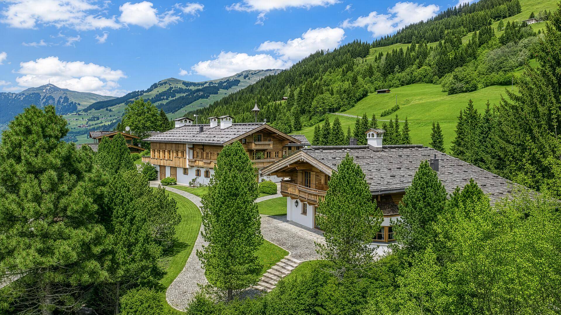 Panoramablick auf das luxuriöse Chalet-Anwesen in einer sonnigen Berglandschaft.