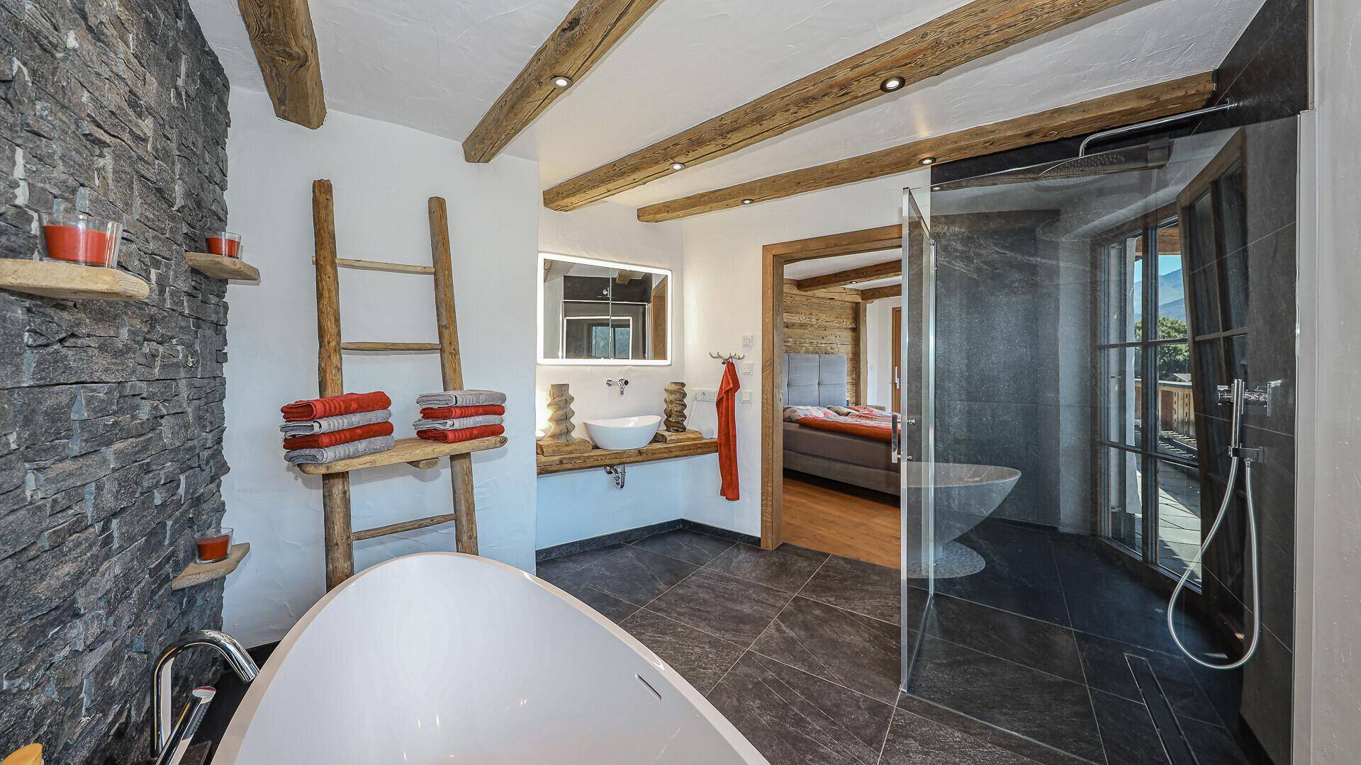 Elegantes Badezimmer mit freistehender Badewanne, Dusche und direktem Zugang zum Schlafzimmer.