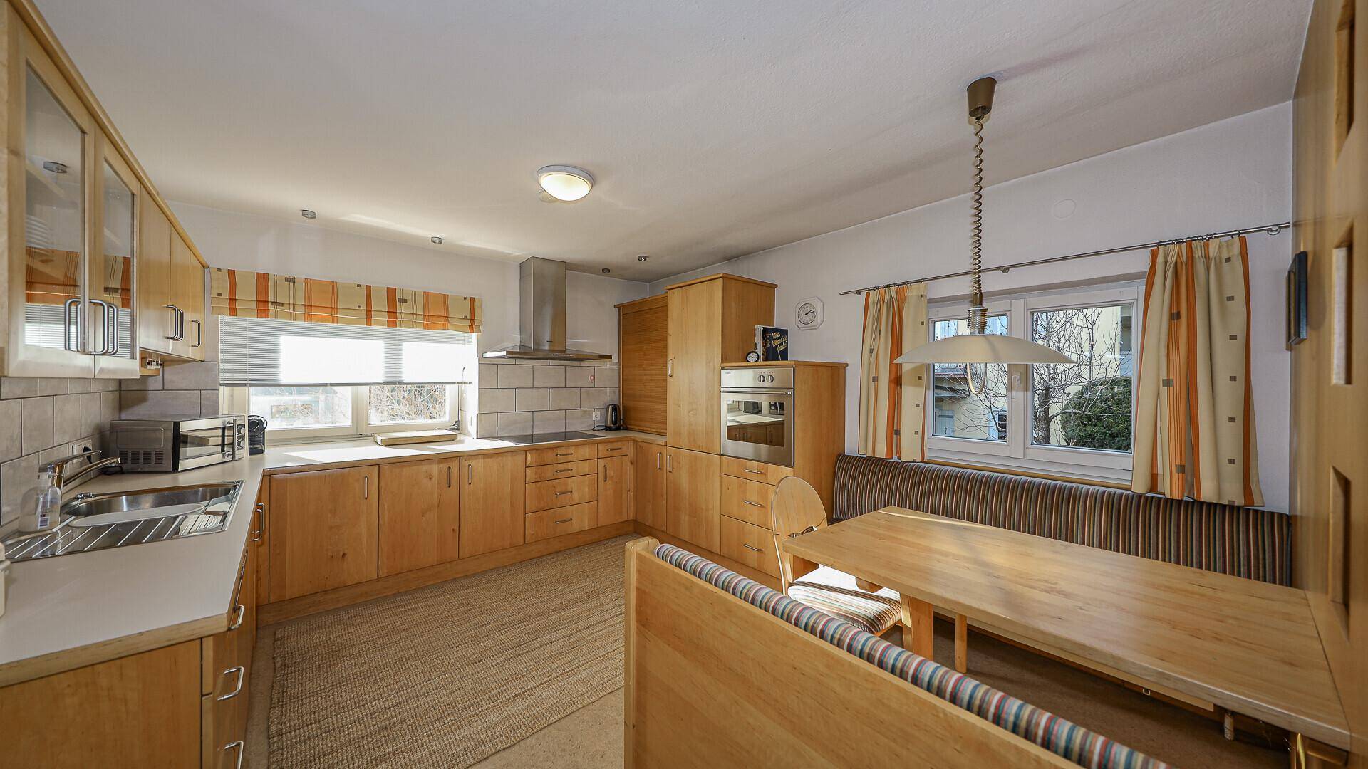 Helle Küche im traditionellen Stil mit Holzeinbauten, Essbereich und Blick nach draußen.