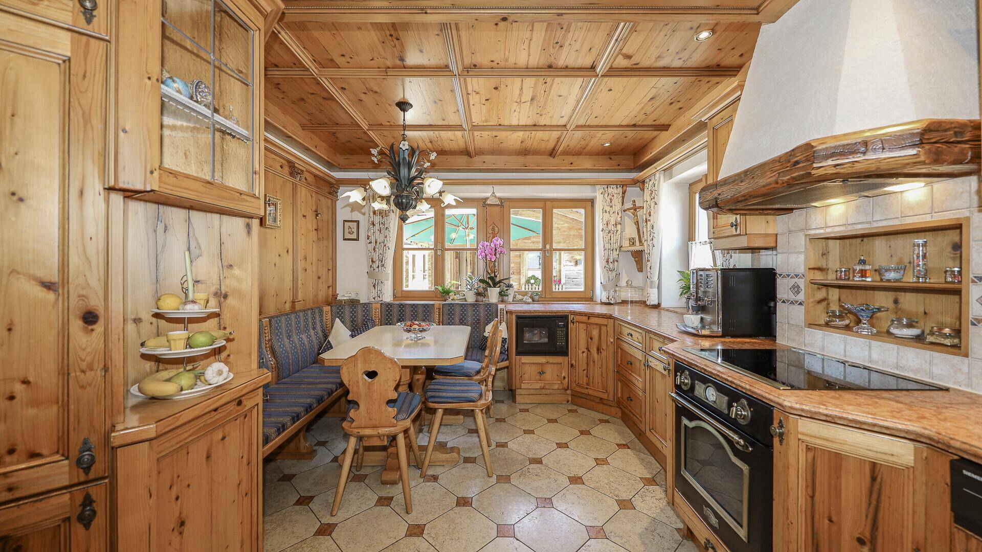 Gemütliche Landhausküche mit Holzelementen, Fliesenboden und integrierter Essecke.