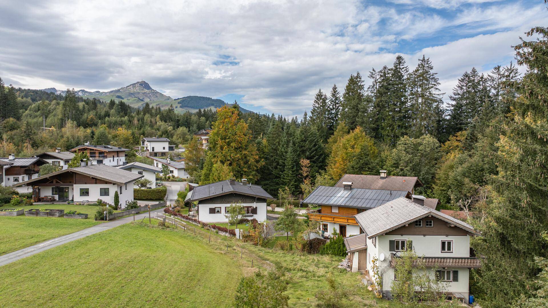 Blick auf eine Ansammlung von Häusern in einer ländlichen Umgebung, umgeben von üppiger Natur und Bergen.