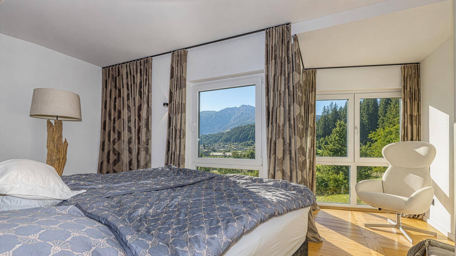 Helles Schlafzimmer mit Doppelbett und großen Fenstern, die einen herrlichen Blick auf die Berge bieten.