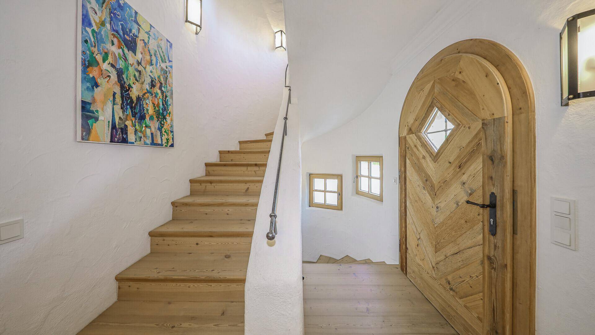 Treppenhaus mit Holztüren und Fenstern, die viel Licht hereinlassen.
