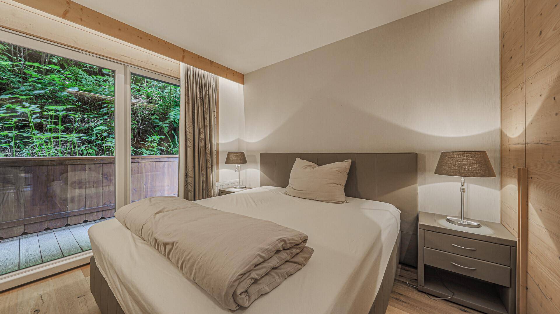 Helles Schlafzimmer mit Holzboden, Doppelbett und direktem Zugang zum Balkon.