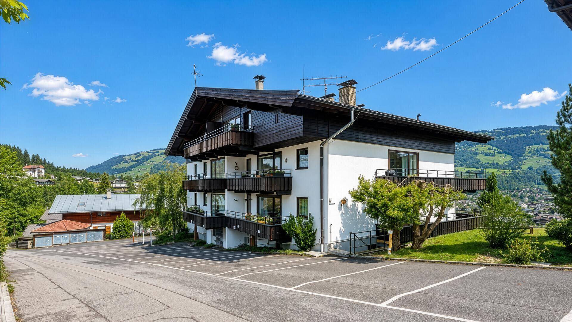 Mehrstöckiges Gebäude mit traditioneller Architektur, Balkonen und Parkplätzen im Freien.