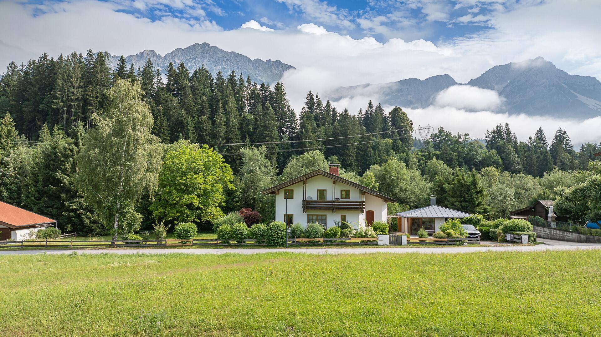 Malerisches Haus im Grünen mit traditionellen Holzelementen und einem weitläufigen Blick auf die umliegende Bergwelt.