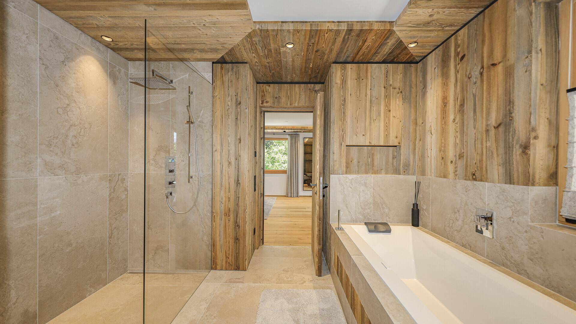 Elegantes Badezimmer mit Badewanne, begehbarer Dusche und Holzelementen.
