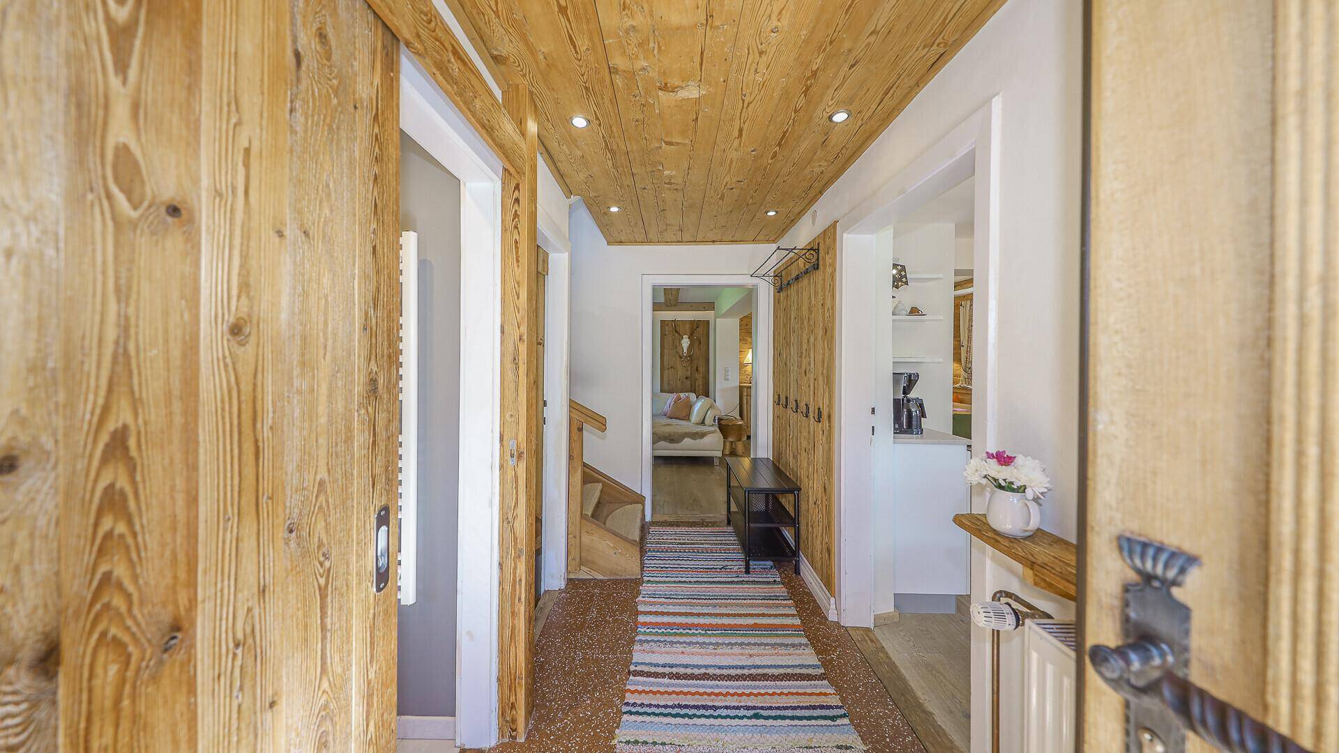 Eingangsbereich mit Holzvertäfelung, Garderobe und Blick in den Wohnbereich.