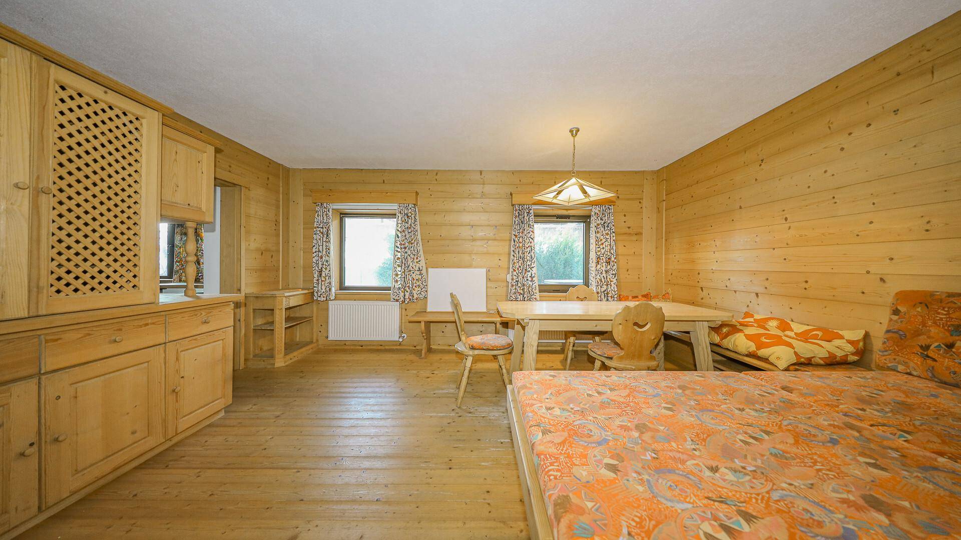 Schlafzimmer im alpinen Stil mit Holzdielenboden, Holzvertäfelung und integrierten Möbeln.