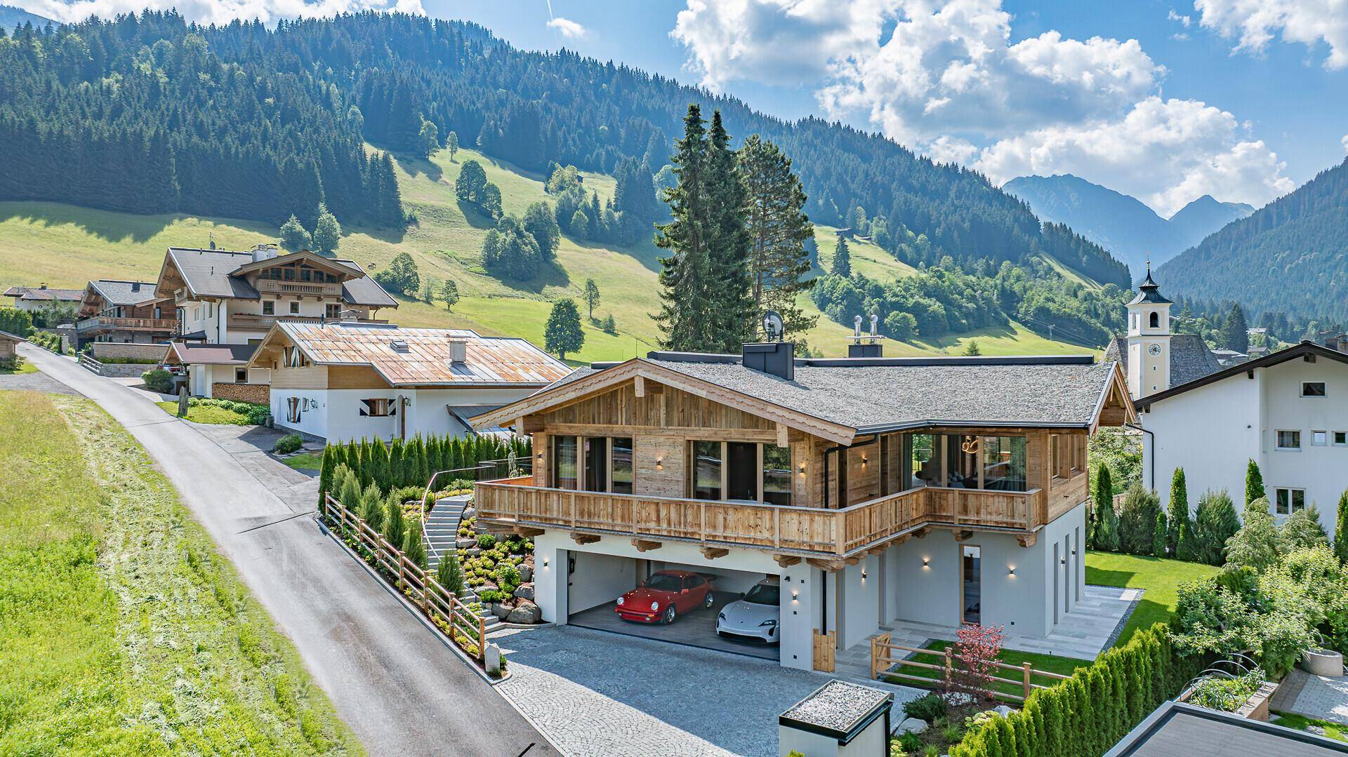 Elegantes Chalet mit integrierter Garage und traditioneller Holzfassade in alpiner Umgebung.