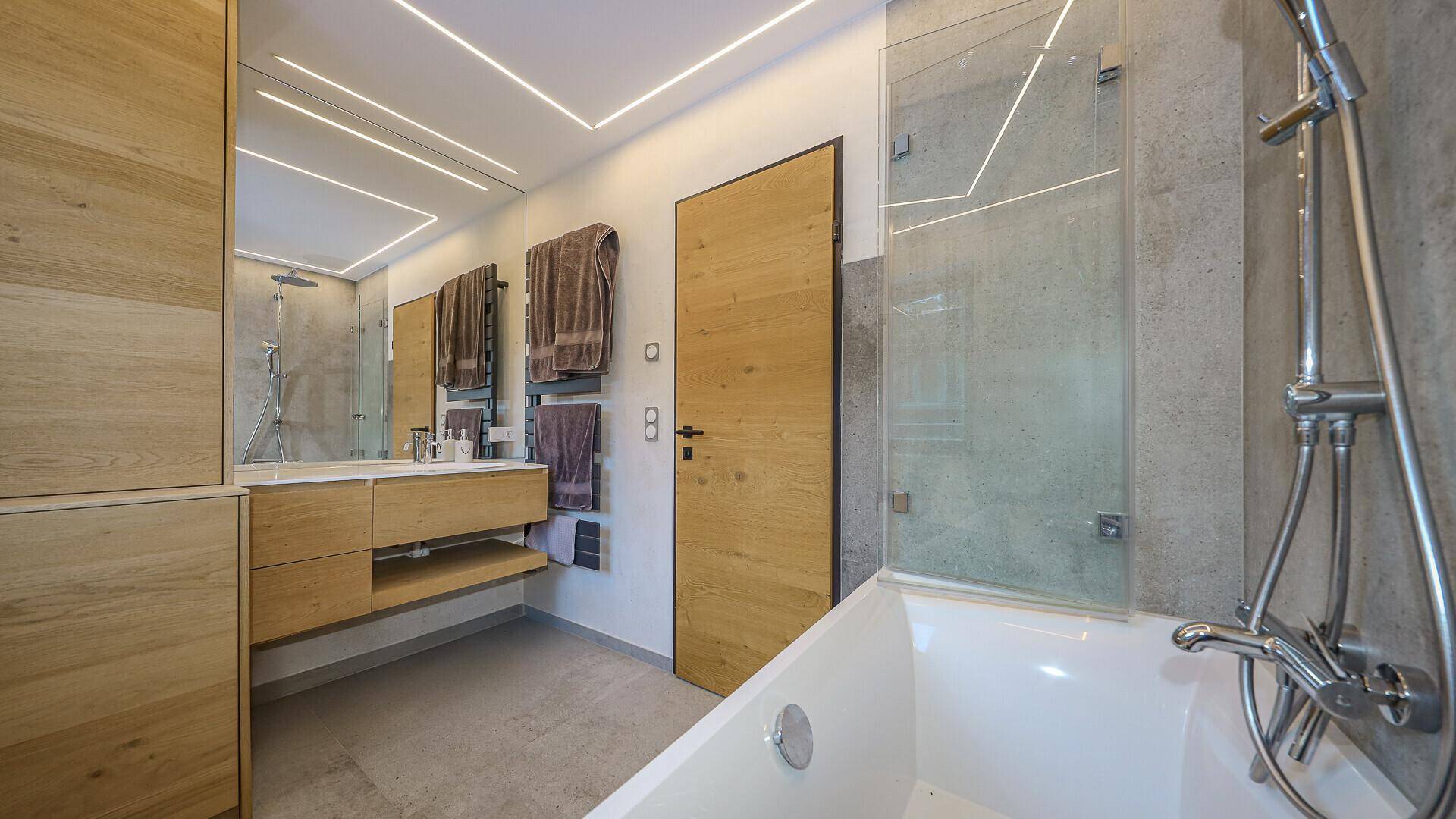 Modernes Badezimmer mit Badewanne, begehbarer Dusche und beheiztem Handtuchhalter.