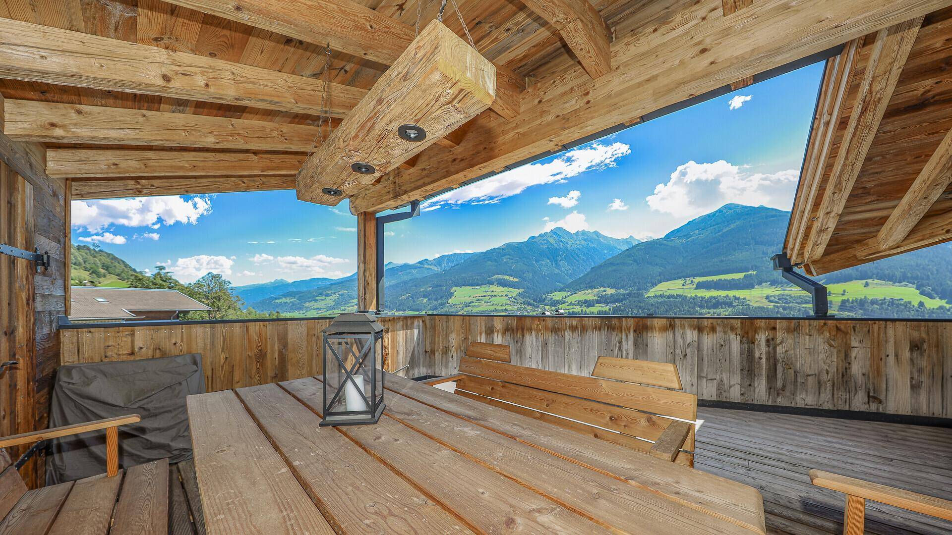 Gemütlicher Holzbalkon mit Esstisch und weitem Blick auf die umliegende Bergwelt.