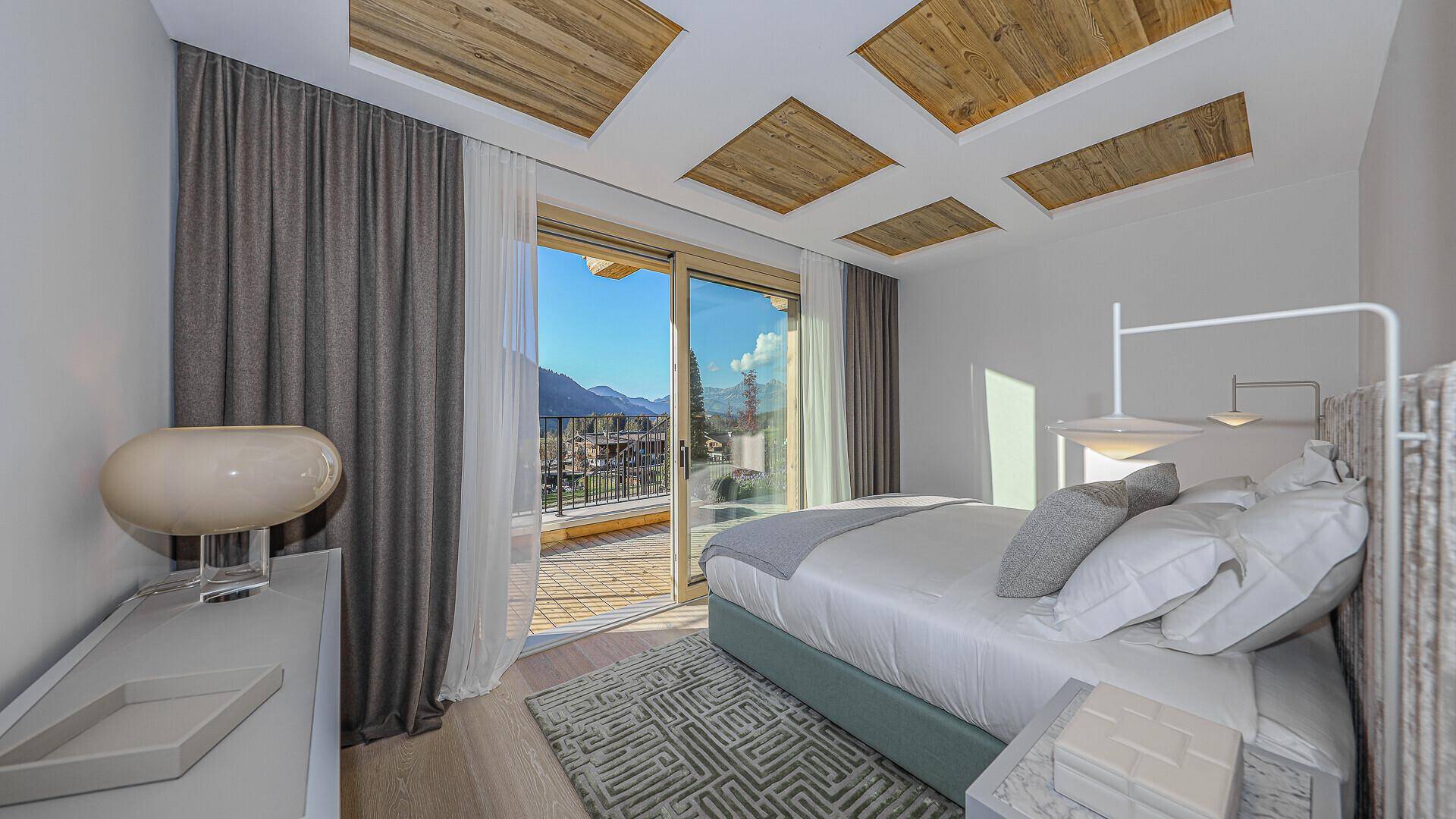 Gemütliches Schlafzimmer mit Balkonzugang und weitem Blick auf die Berglandschaft.