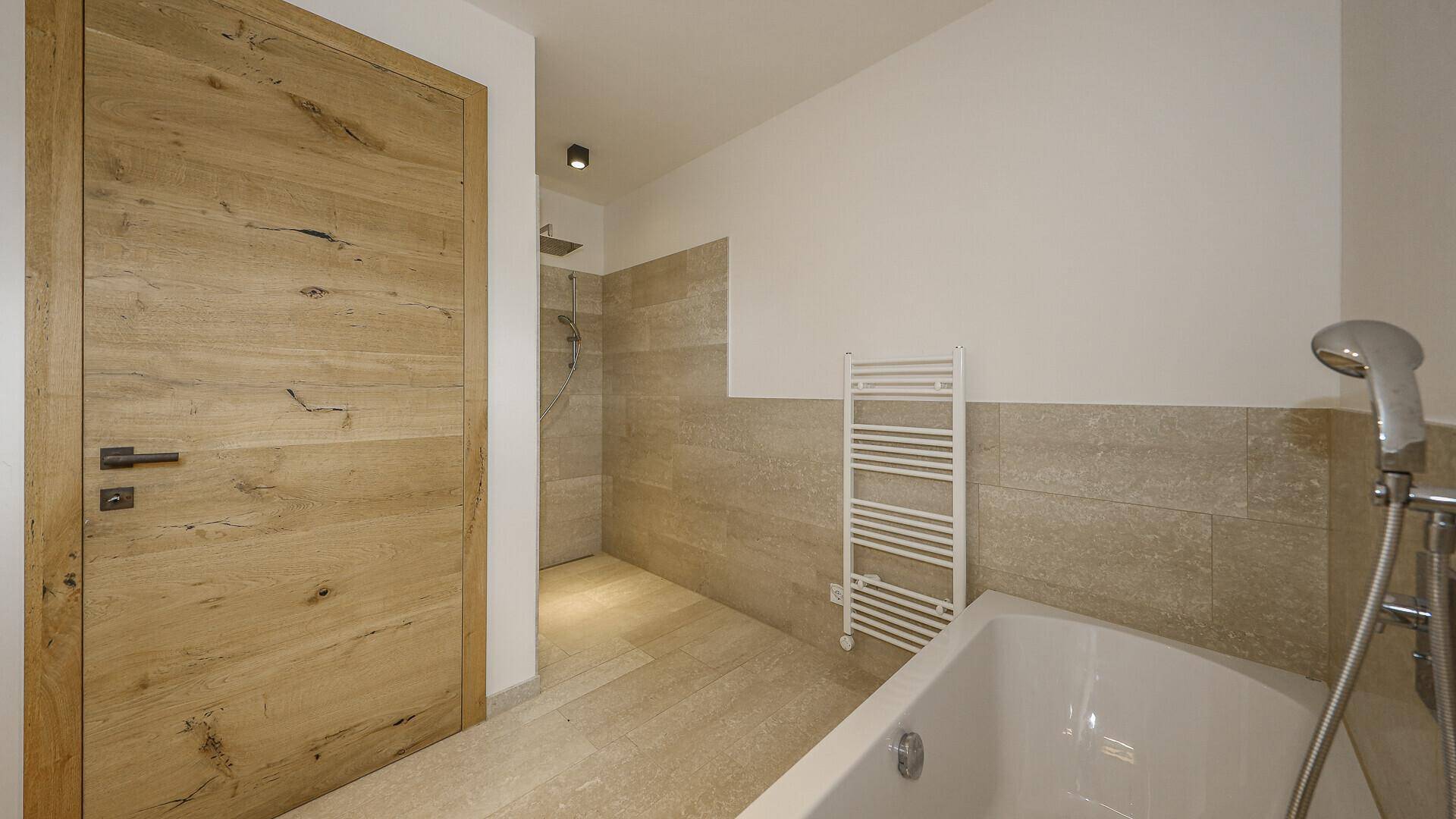 Modernes Badezimmer mit Badewanne, ebenerdiger Dusche und beheiztem Handtuchhalter.