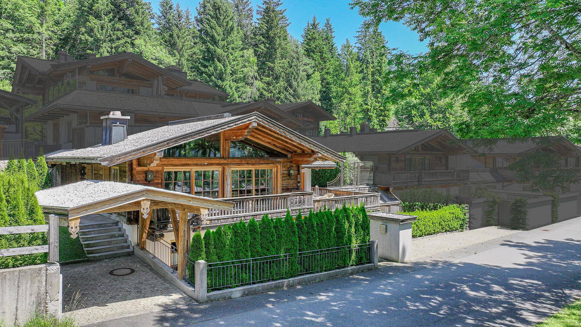 Charmantes Holzchalet mit traditioneller Architektur, Carport und Balkon, umgeben von grünen Bäumen.