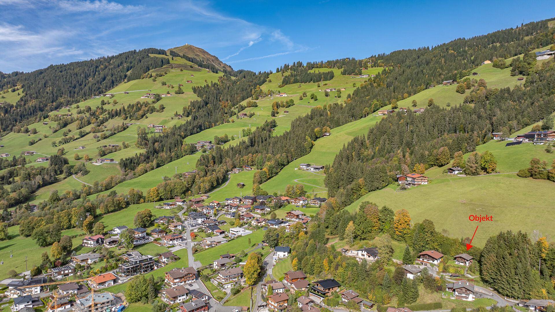 Luftaufnahme der Immobilie in einer malerischen alpinen Landschaft mit Bergen und Dorf.