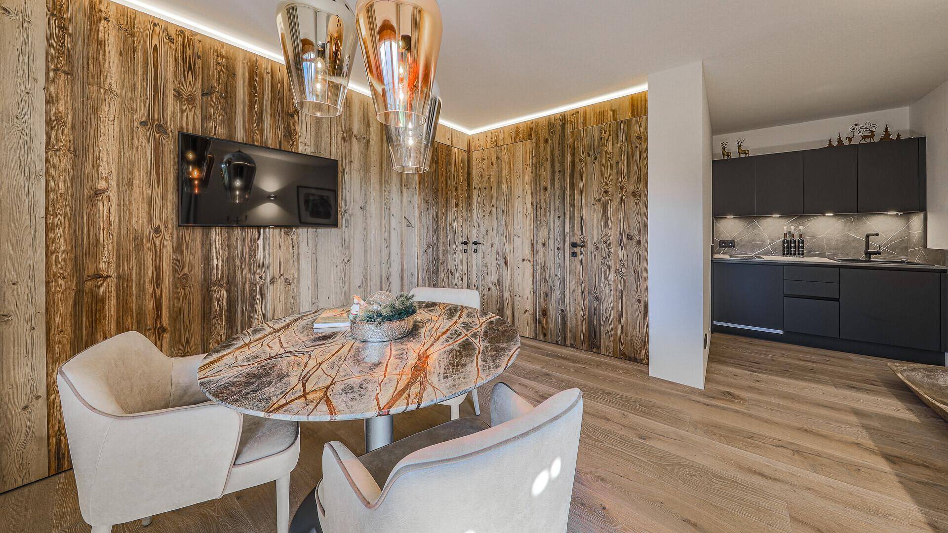 Moderner Essbereich mit Holzwänden, ovalem Tisch und Blick auf die angrenzende Küche.