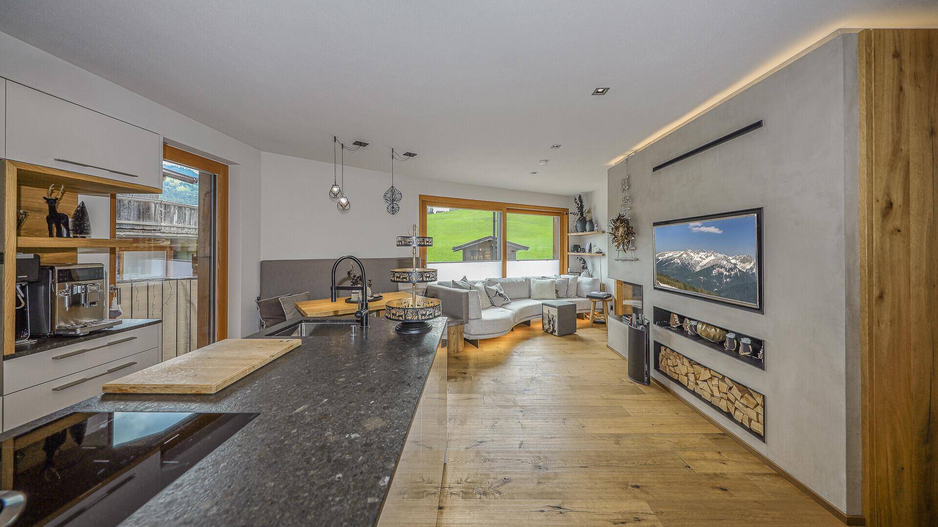 Heller Wohnbereich mit gemütlicher Sitzecke, Kamin und Bergblick.