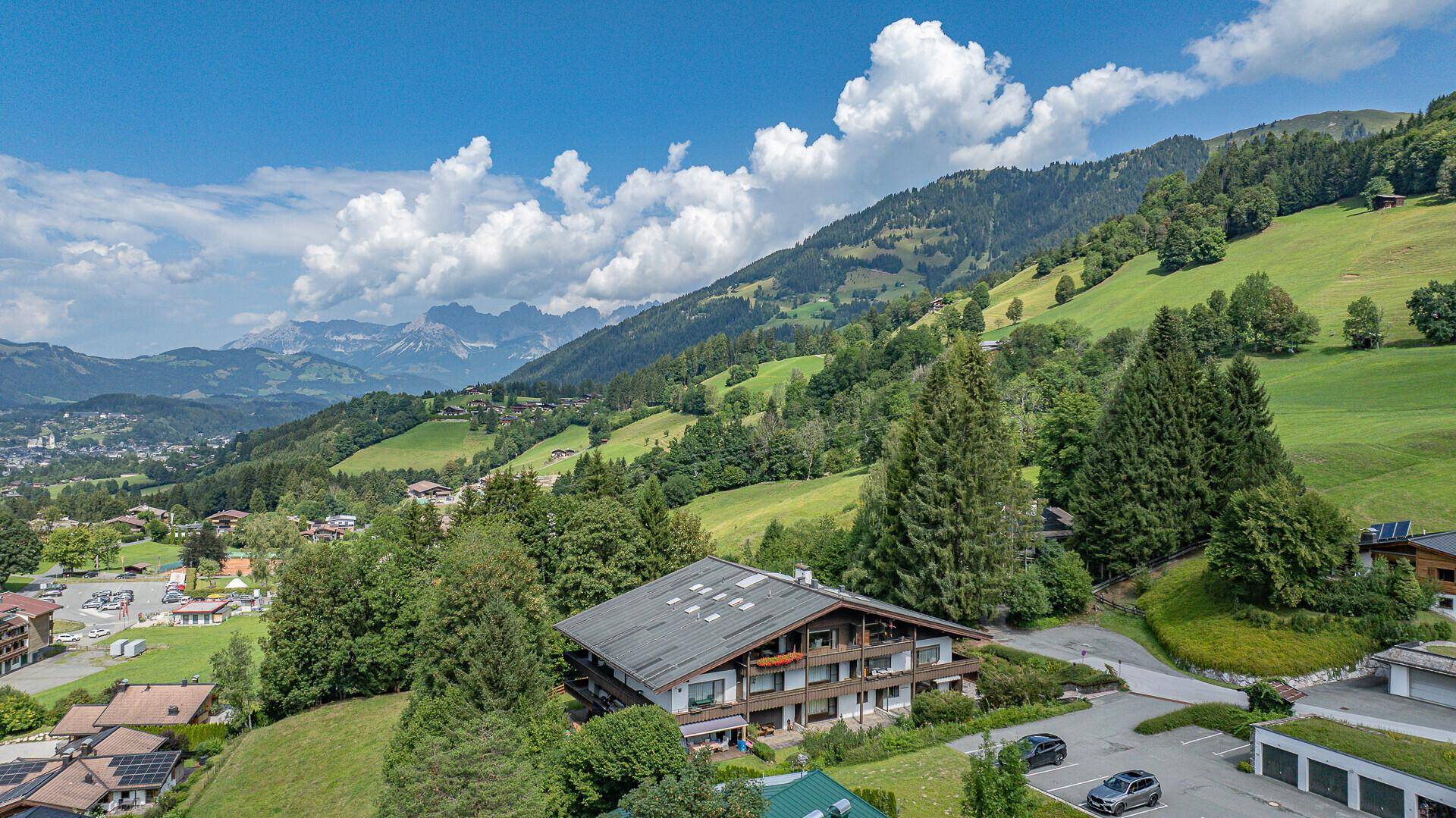Luftaufnahme des Anwesens in einer malerischen Berglandschaft mit grünen Hügeln und Wäldern.