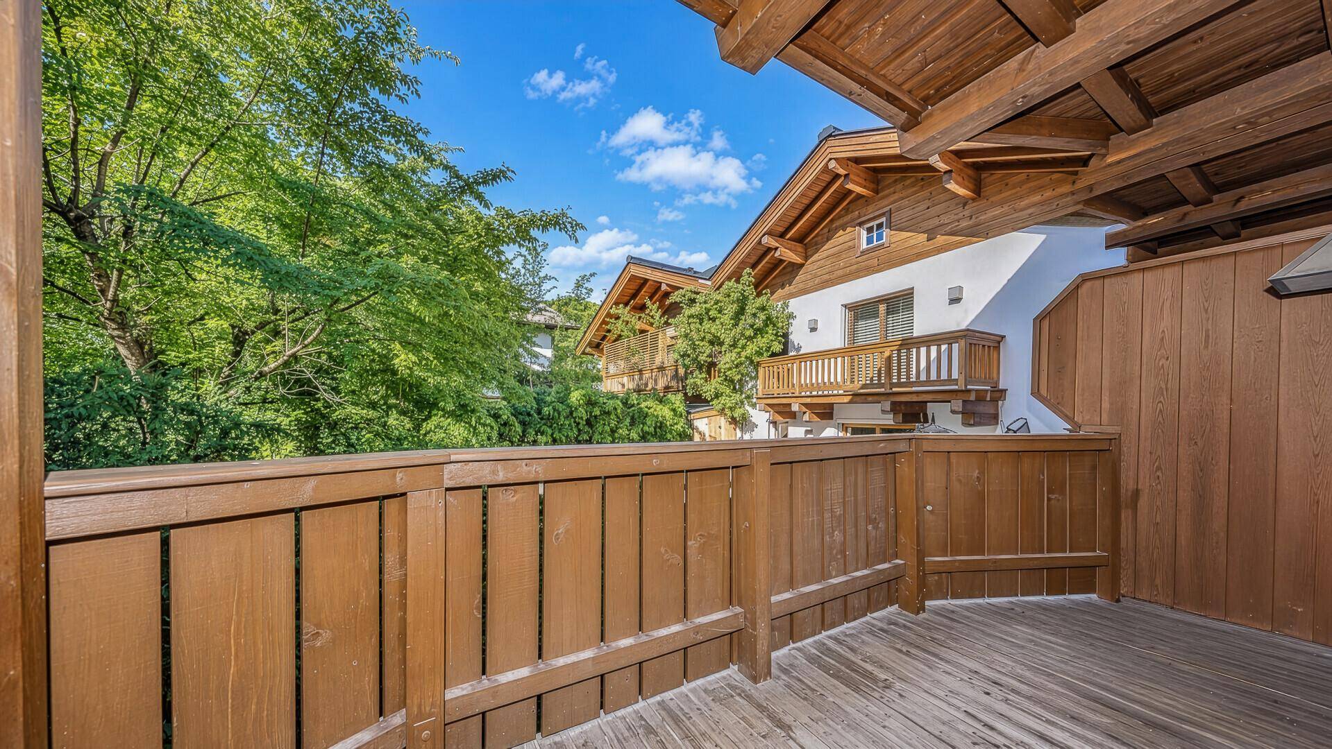 Geräumiger Holzbalkon mit Blick auf die umliegenden Häuser und viel Grün.