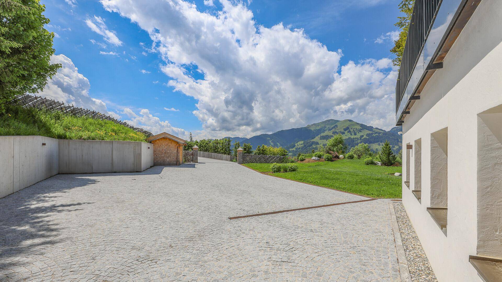Geräumige Auffahrt mit Kopfsteinpflaster und Blick auf die umliegende Berglandschaft.