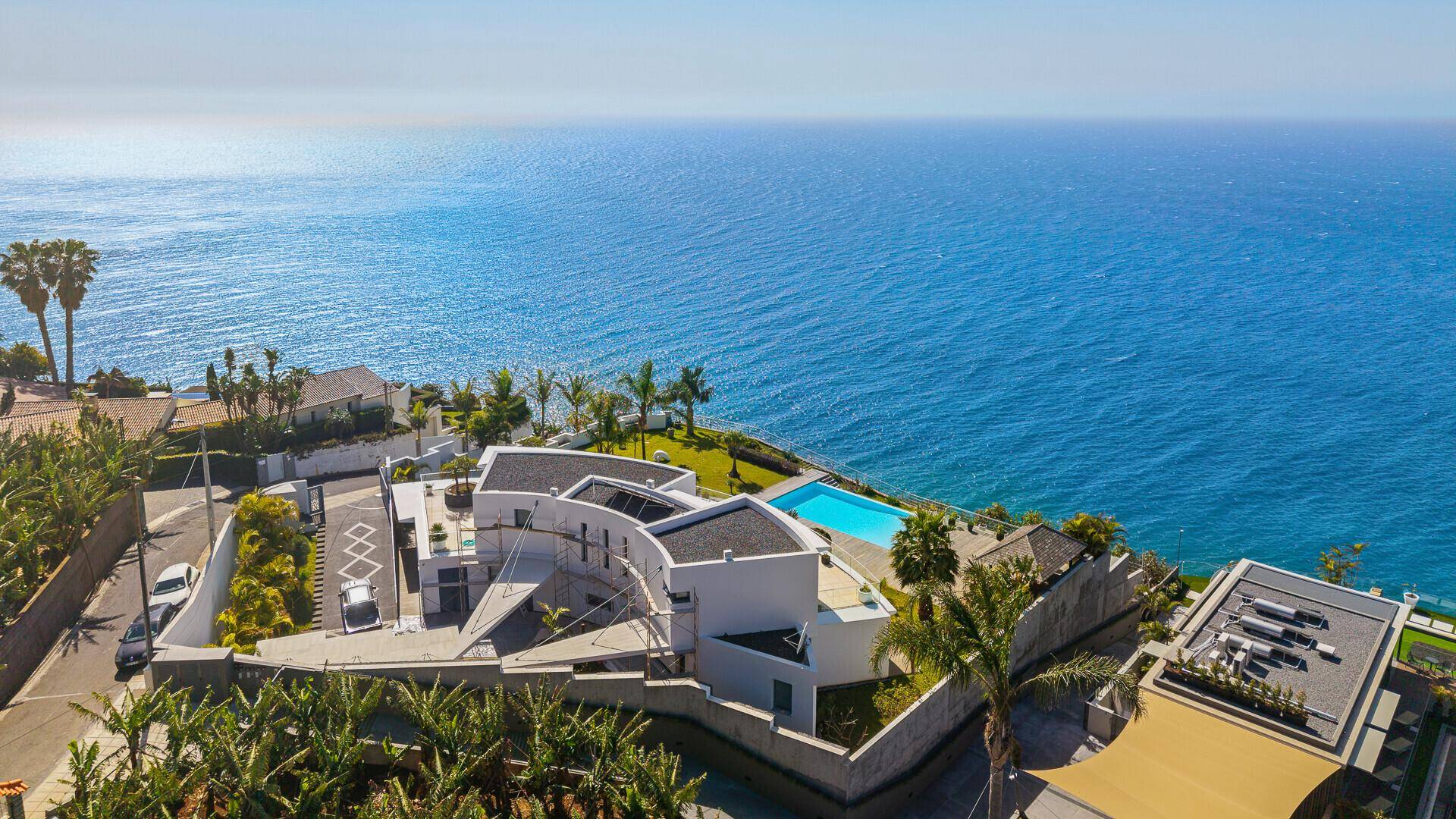 Luftaufnahme der modernen Villa mit Pool, Meerblick und der umliegenden grünen Landschaft.