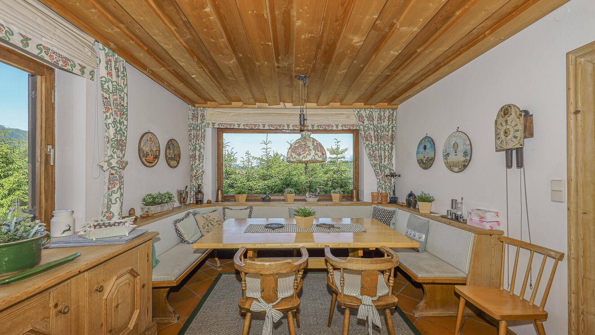 Traditionelle Essecke mit Holztäfelung, Eckbank und großem Fenster mit Bergblick.