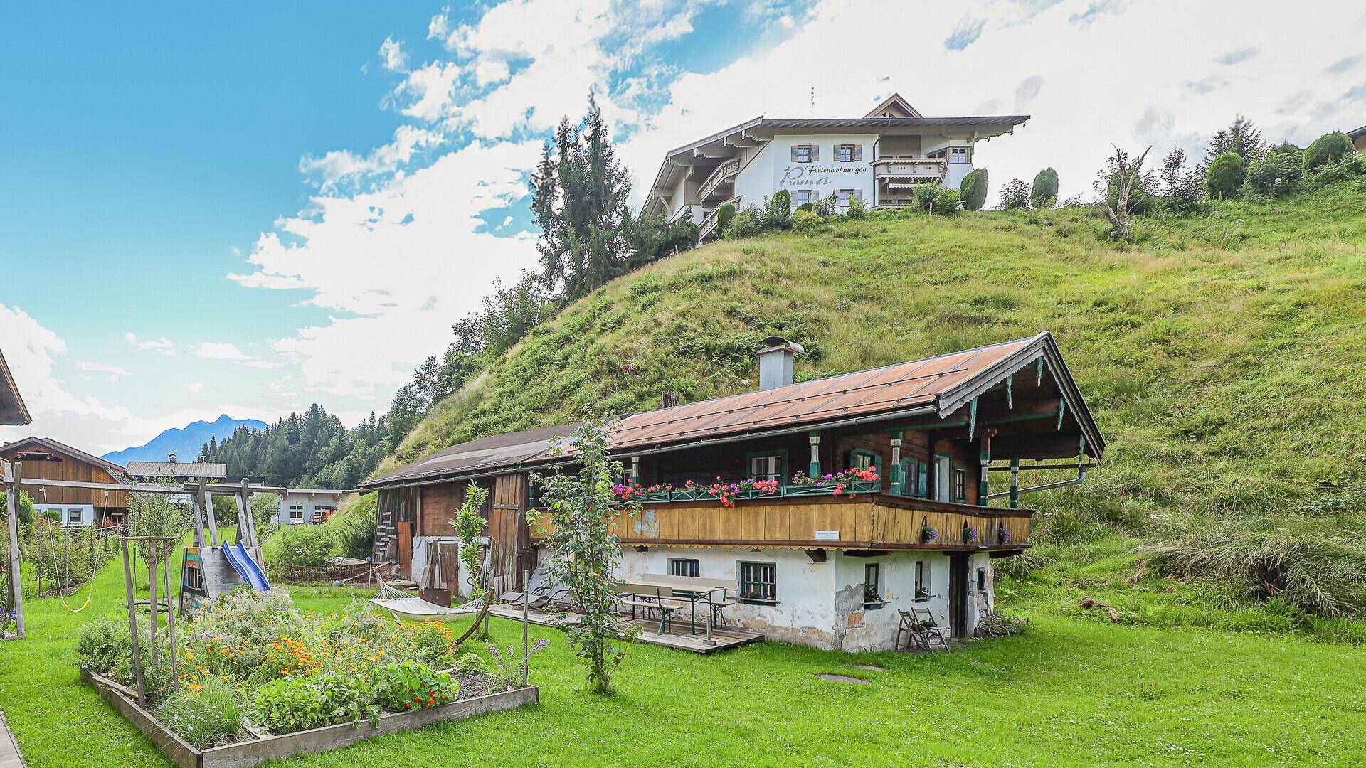 Alpines Holzhaus mit Garten, Spielplatz und Blick auf die umliegende Natur.