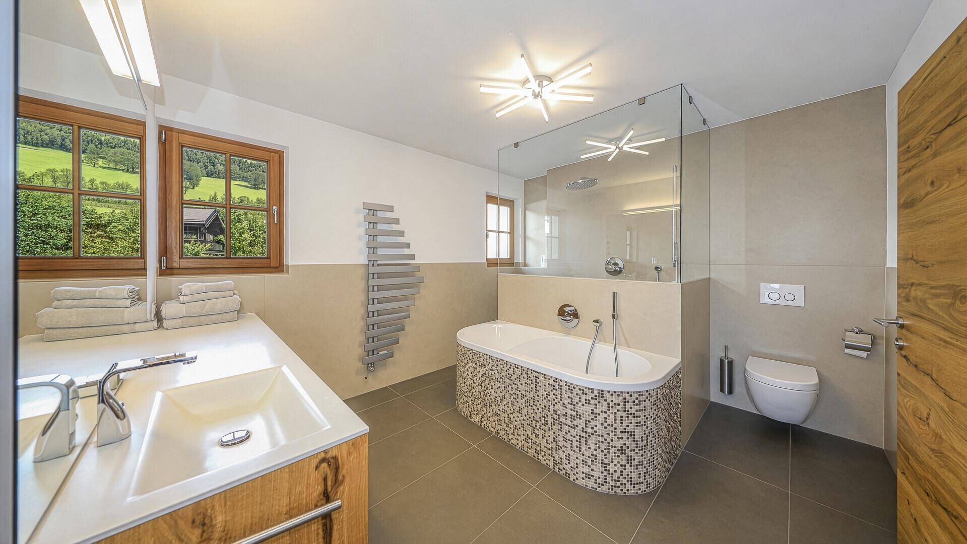 Modernes Badezimmer mit Badewanne, Dusche, Doppelwaschbecken und Fenster.