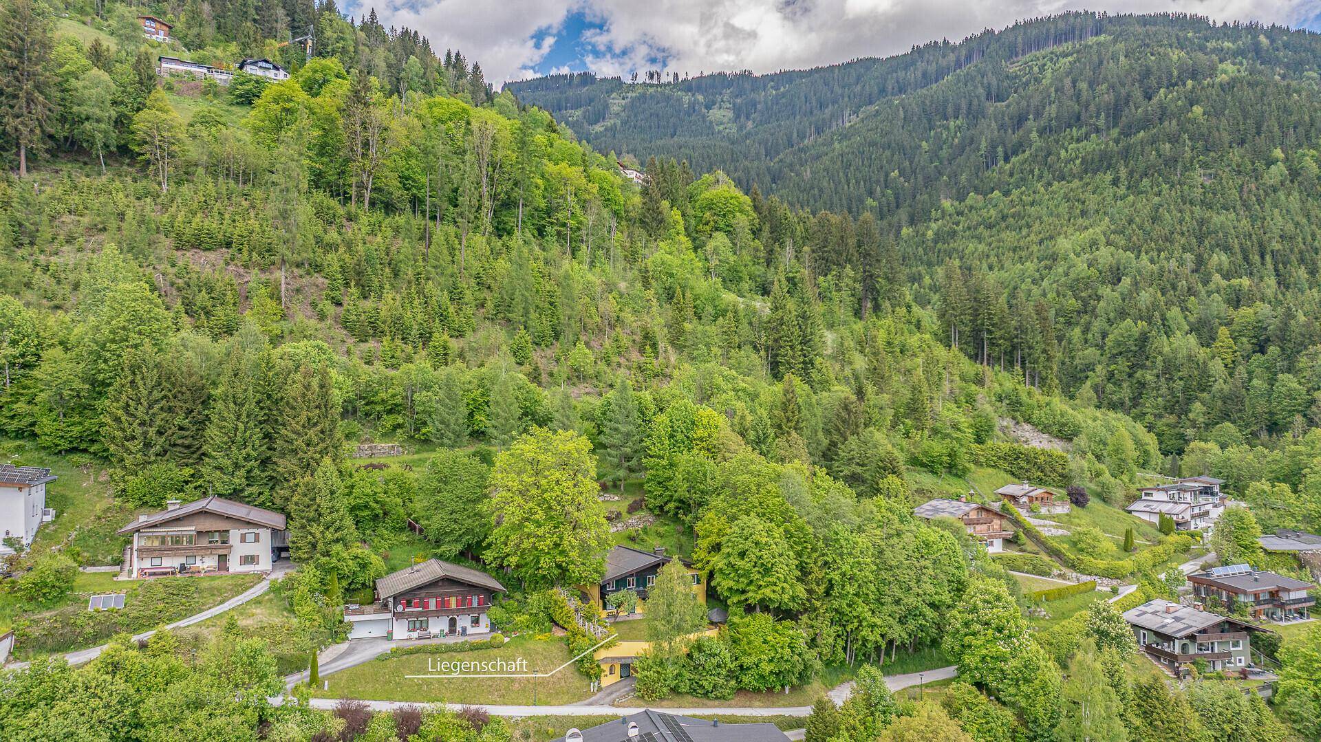 Luftaufnahme der Liegenschaft in einer grünen Hanglandschaft mit umliegenden Häusern.