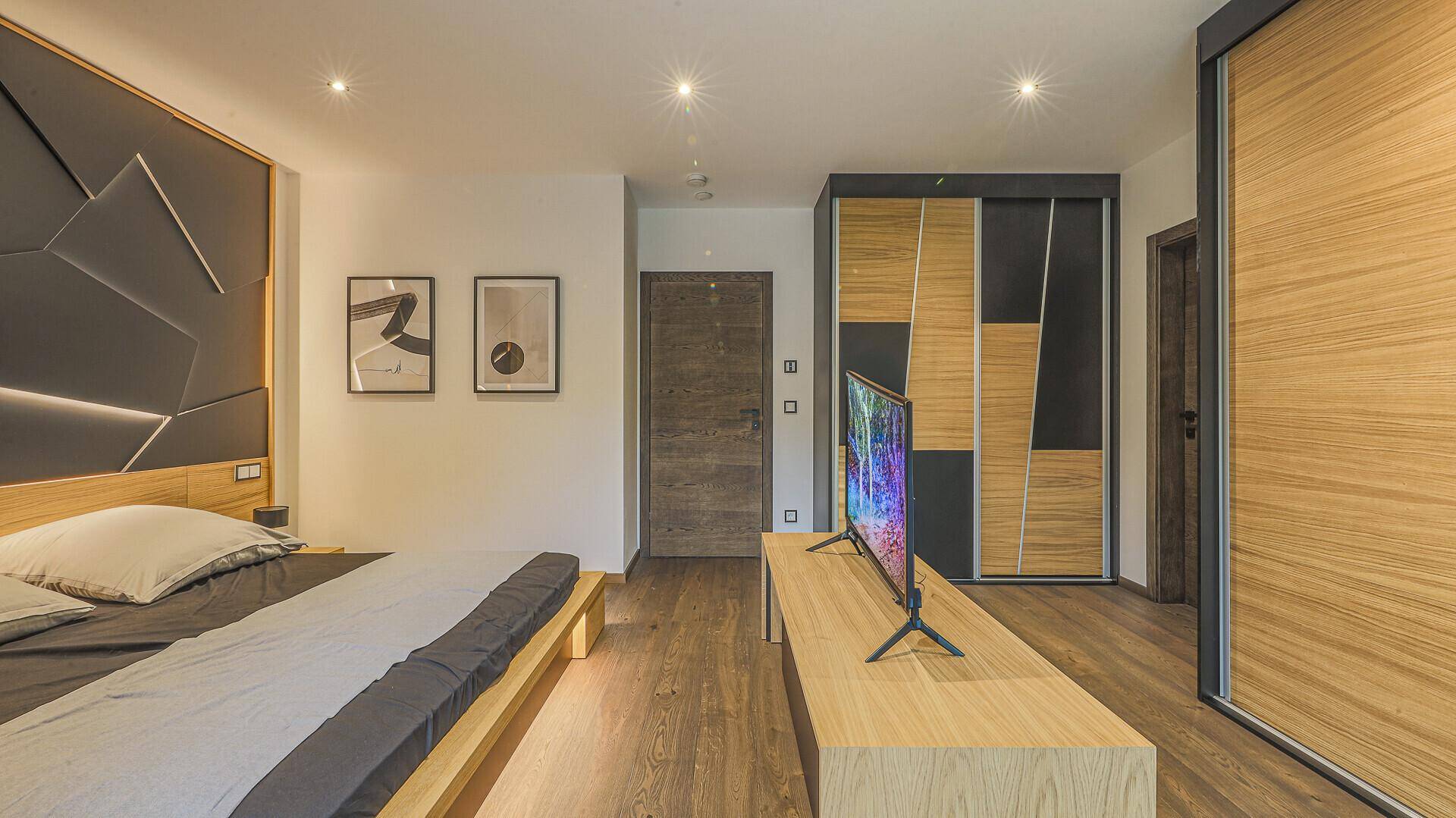 Schlafzimmer mit modernem Design, Holzboden und integrierten Schränken für viel Stauraum.