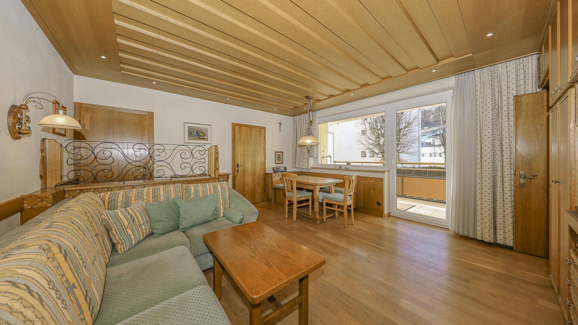 Gemütlicher Wohn-Essbereich im traditionellen Stil mit Holzdecke und Zugang zum Balkon.