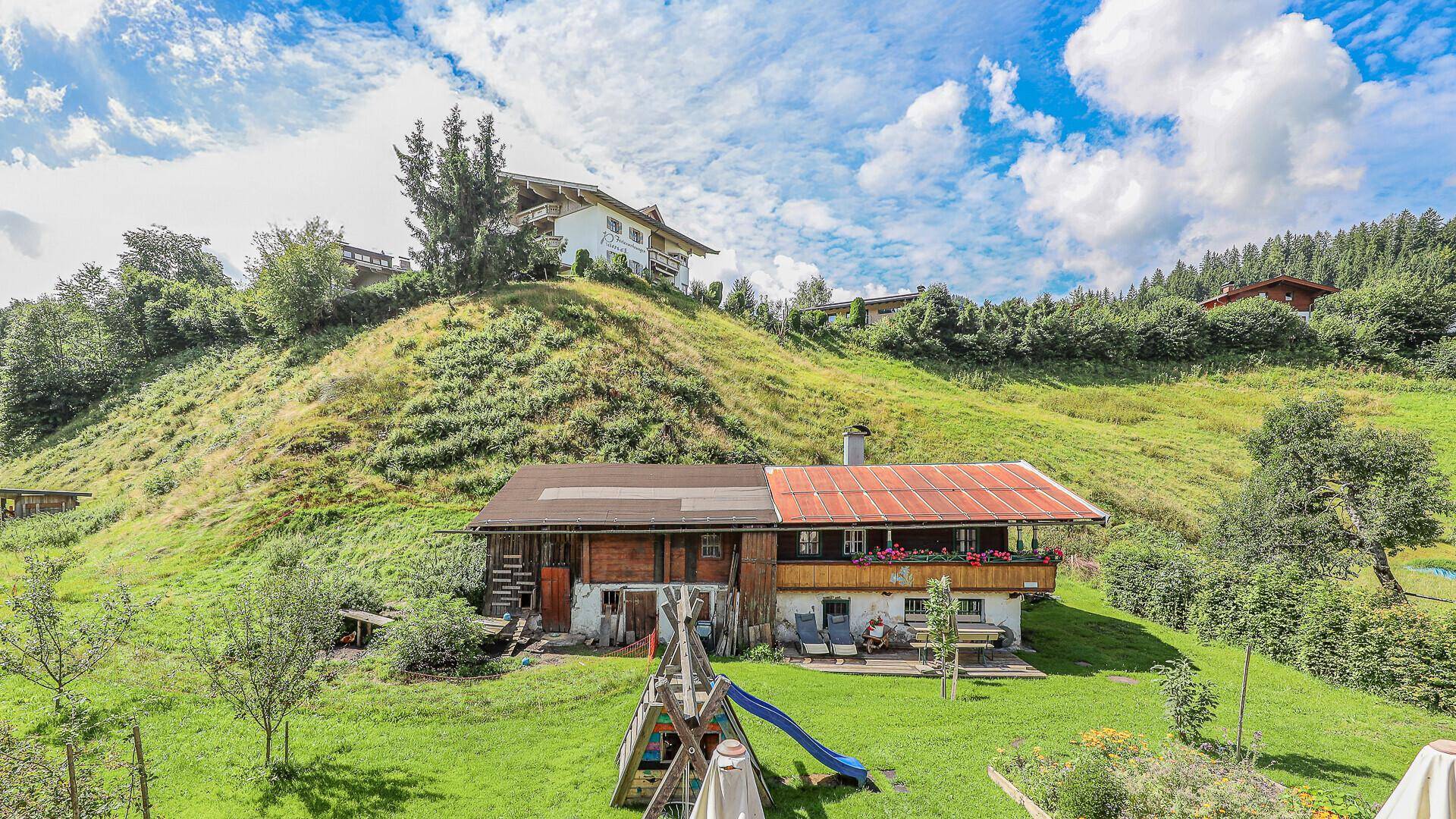 Alpines Anwesen mit großem Garten, Spielplatz und Blick auf die umliegende Berglandschaft.