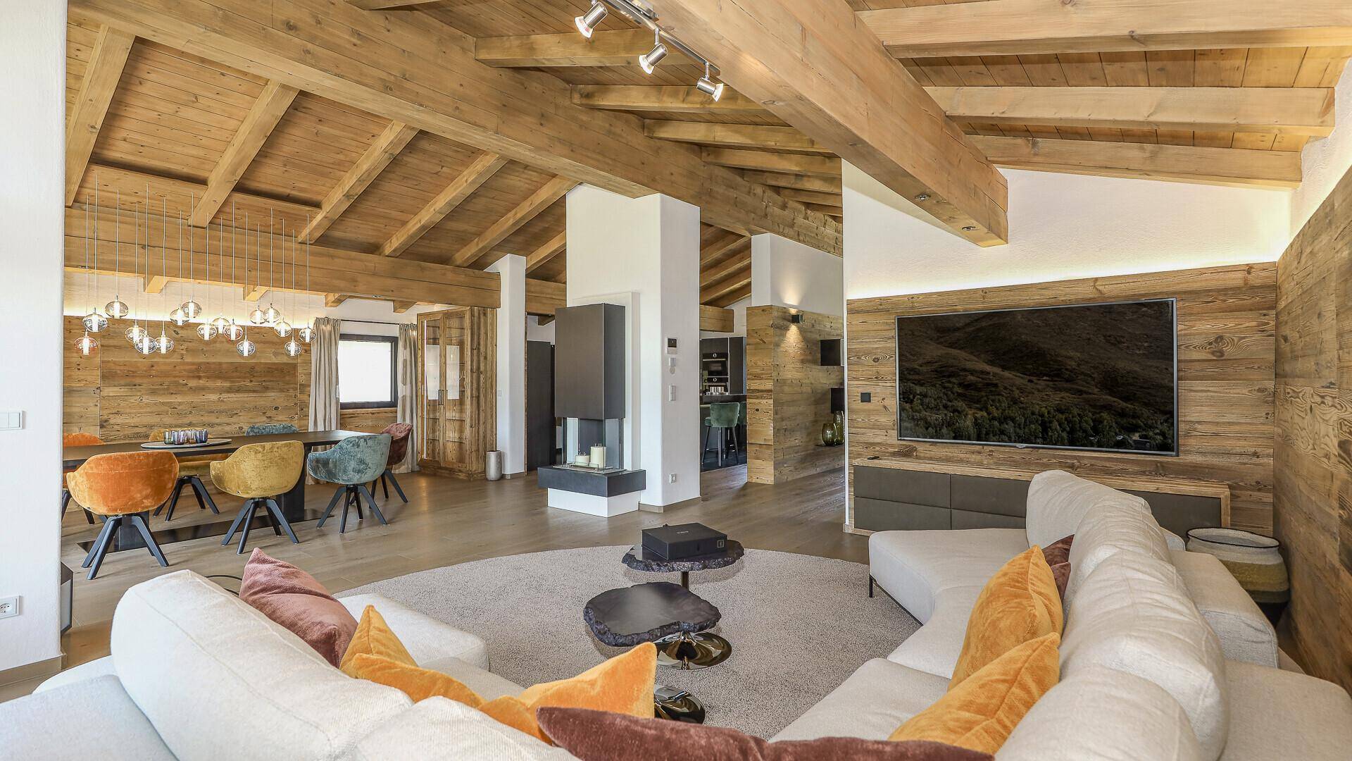 Gemütlicher offener Wohn- und Essbereich mit Holzbalkendecke und modernem Kamin.