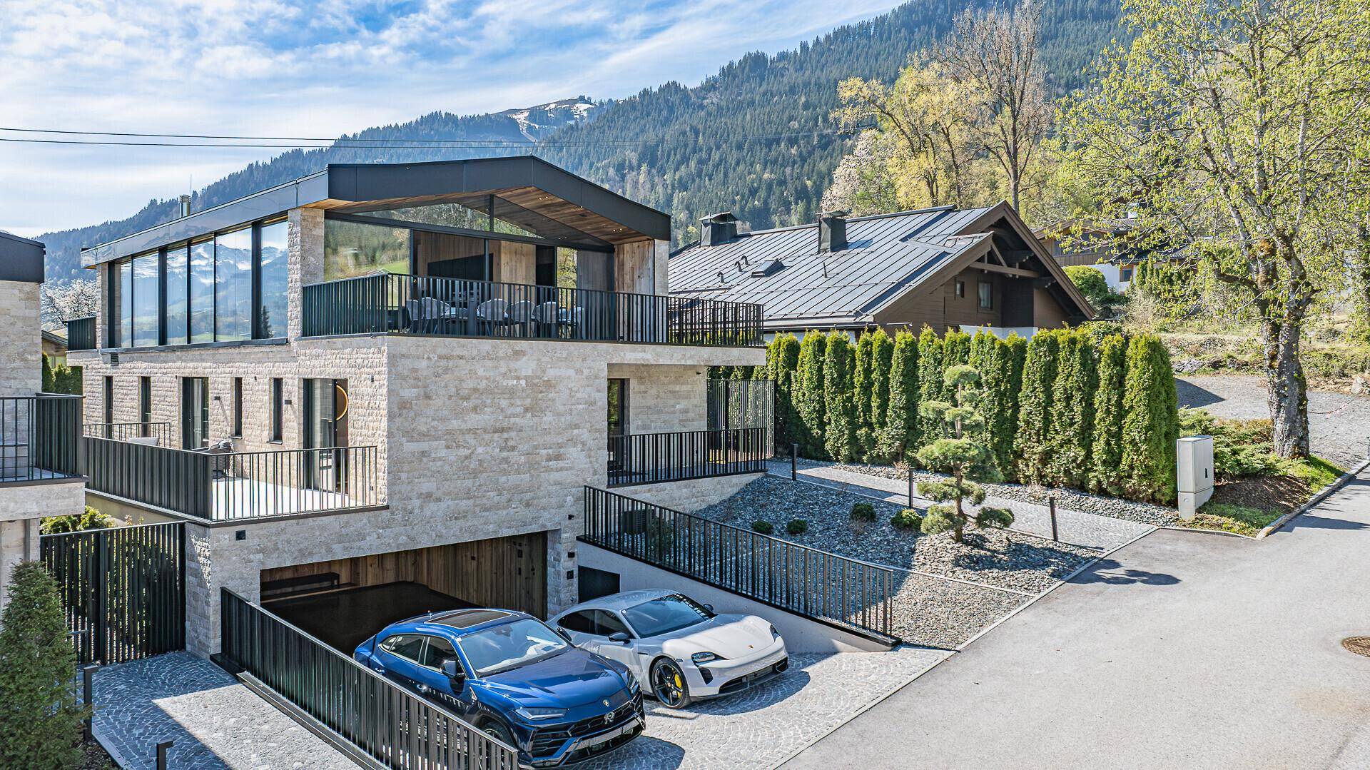 Luxuriöse Villa mit moderner Architektur, Steinfassade und beeindruckendem Bergblick in alpiner Umgebung.
