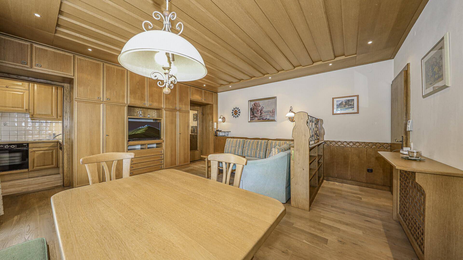 Traditioneller Wohn-Essbereich mit Holzdecke, Einbauschränken und integrierter Küchenzeile.