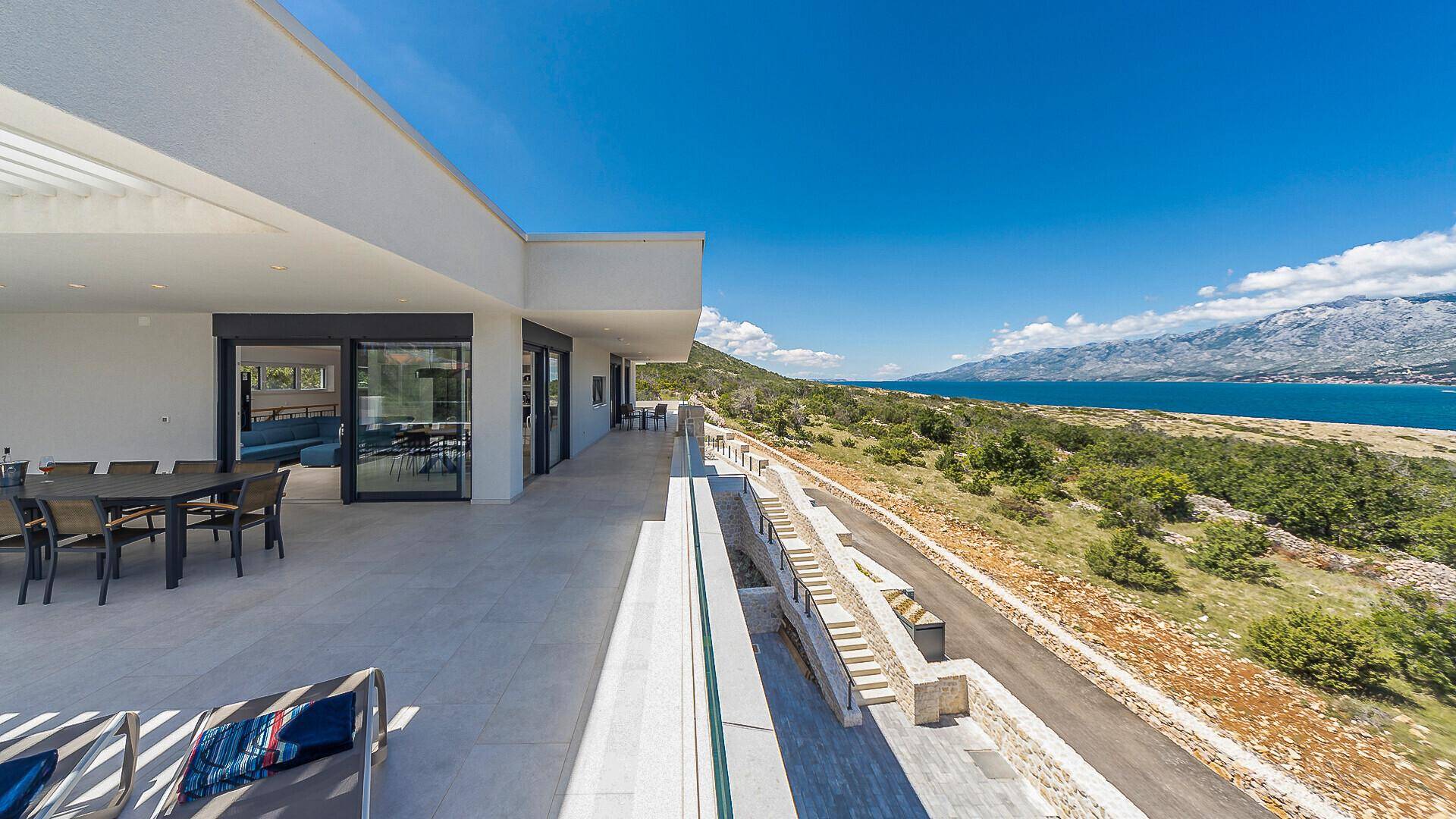 Weitläufige Terrasse mit Glasgeländer, die einen Panoramablick auf die Küste und die umliegende Landschaft bietet.