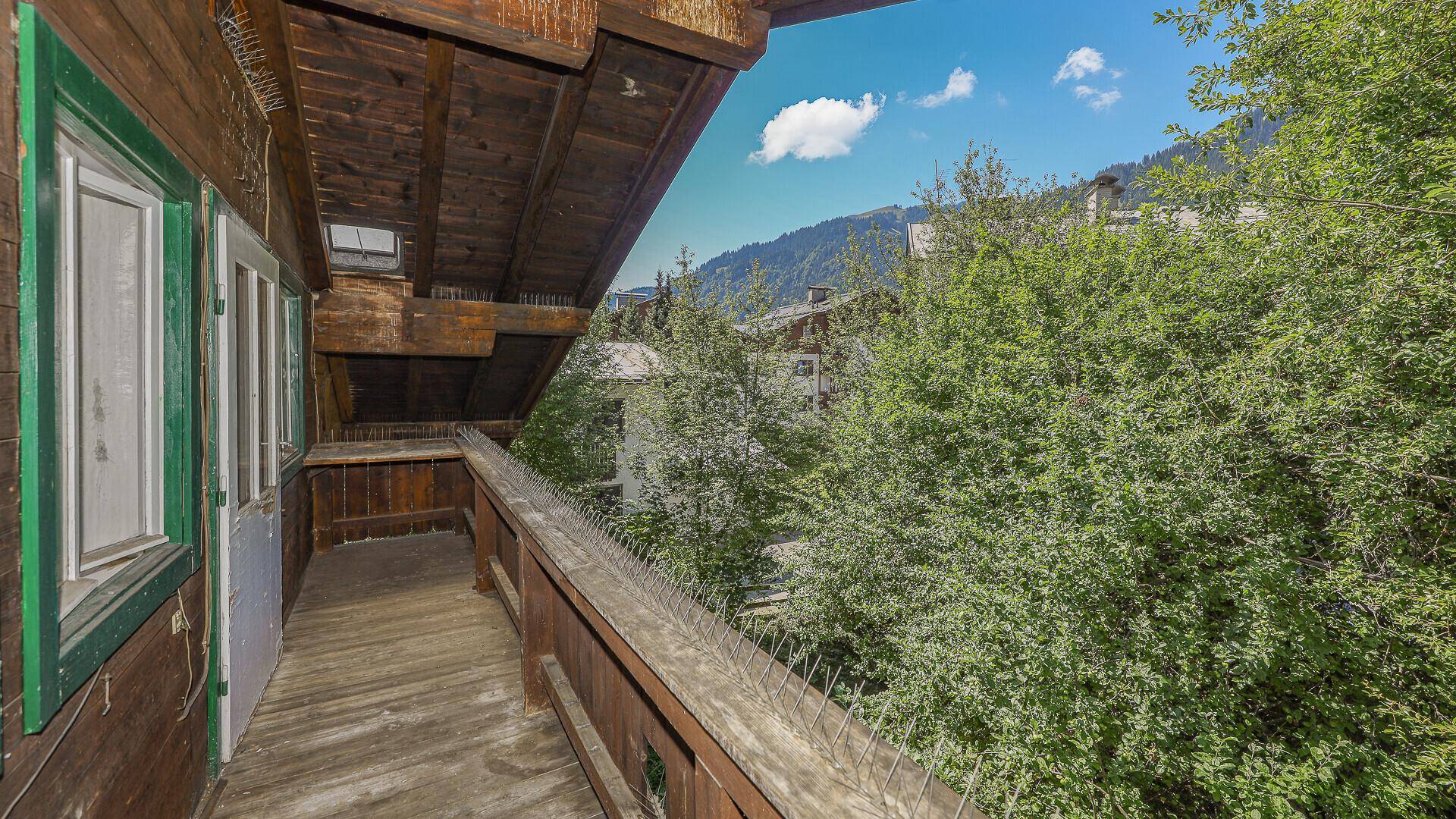 Holzbalkon mit Blick ins Grüne, umgeben von üppigen Bäumen und Sträuchern.