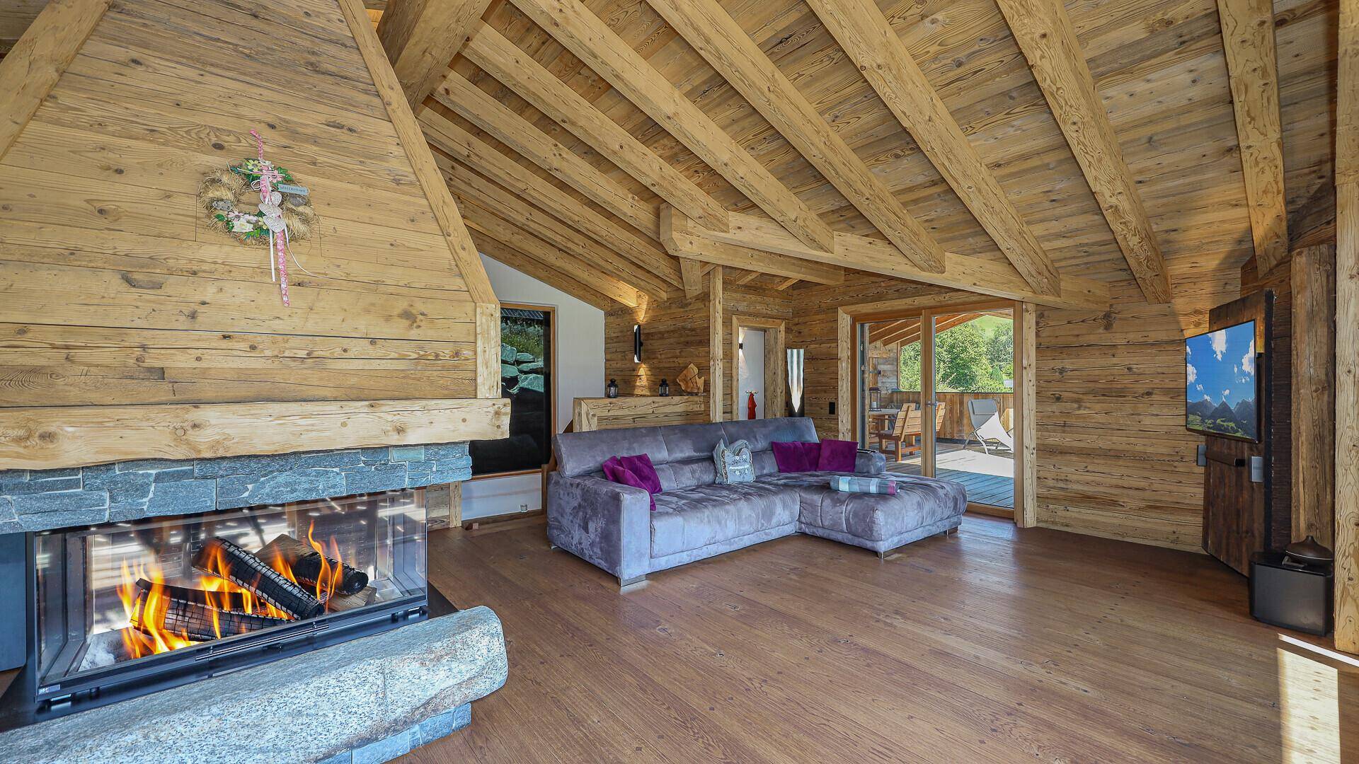 Geräumiger Wohnbereich mit Kamin, Holzbalken und gemütlicher Sitzecke im Chalet-Stil.