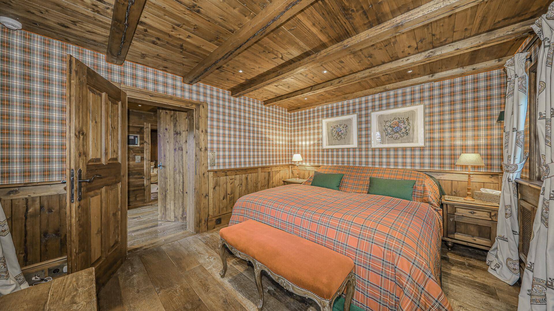 Komfortables Schlafzimmer mit karierter Tapete, Holzbalkendecke und großem Doppelbett.