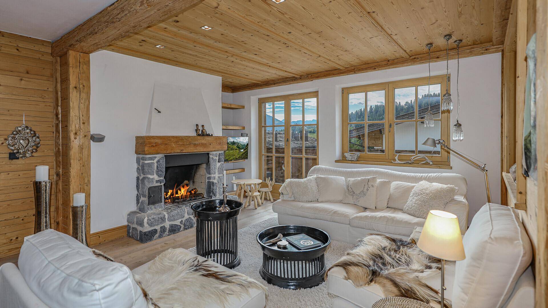 Heller Wohnbereich mit Kamin, bequemen Sofas und Holzbalken, bietet Bergblick.