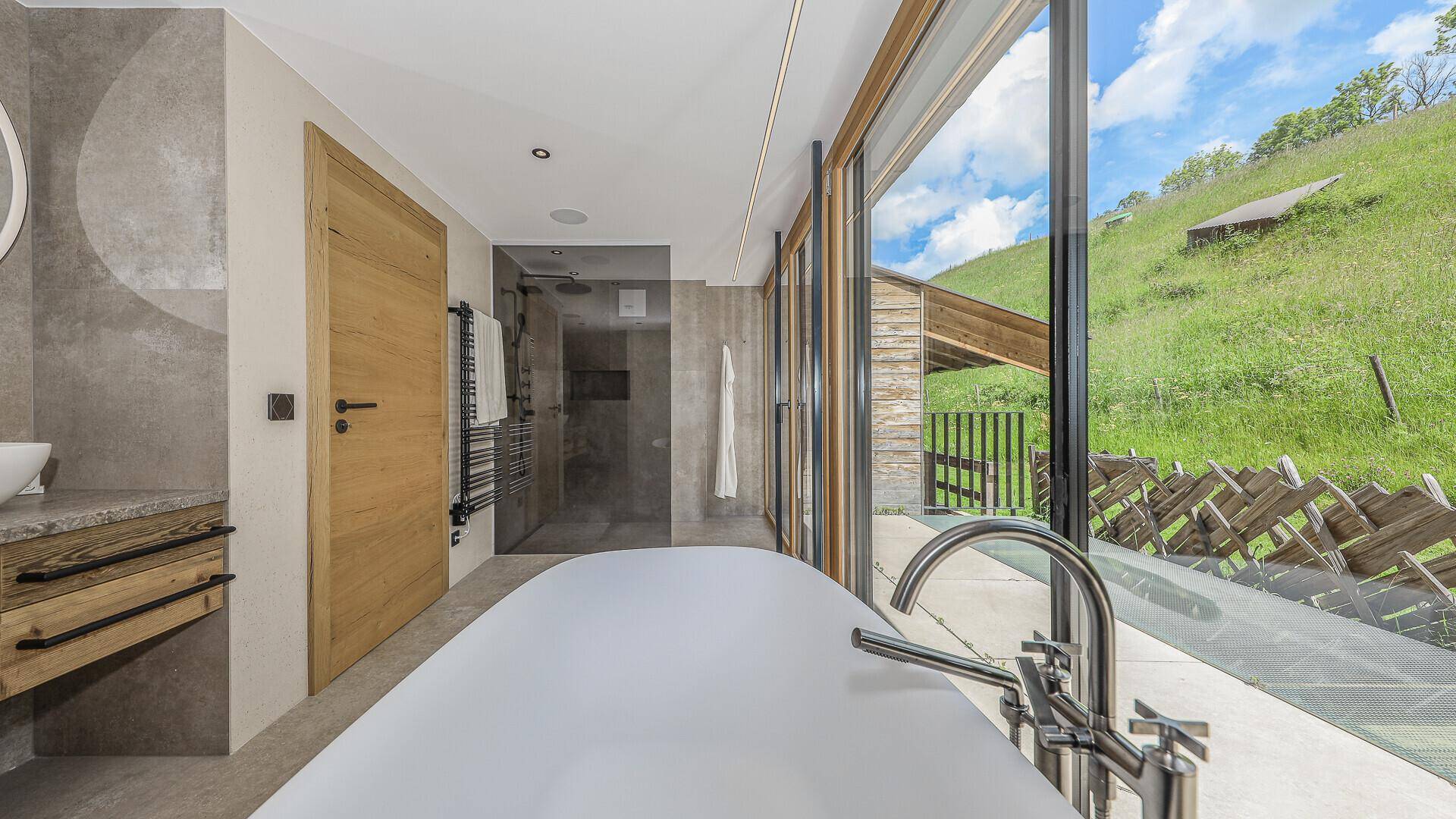 Elegantes Badezimmer mit freistehender Badewanne, begehbarer Dusche und Panoramablick.
