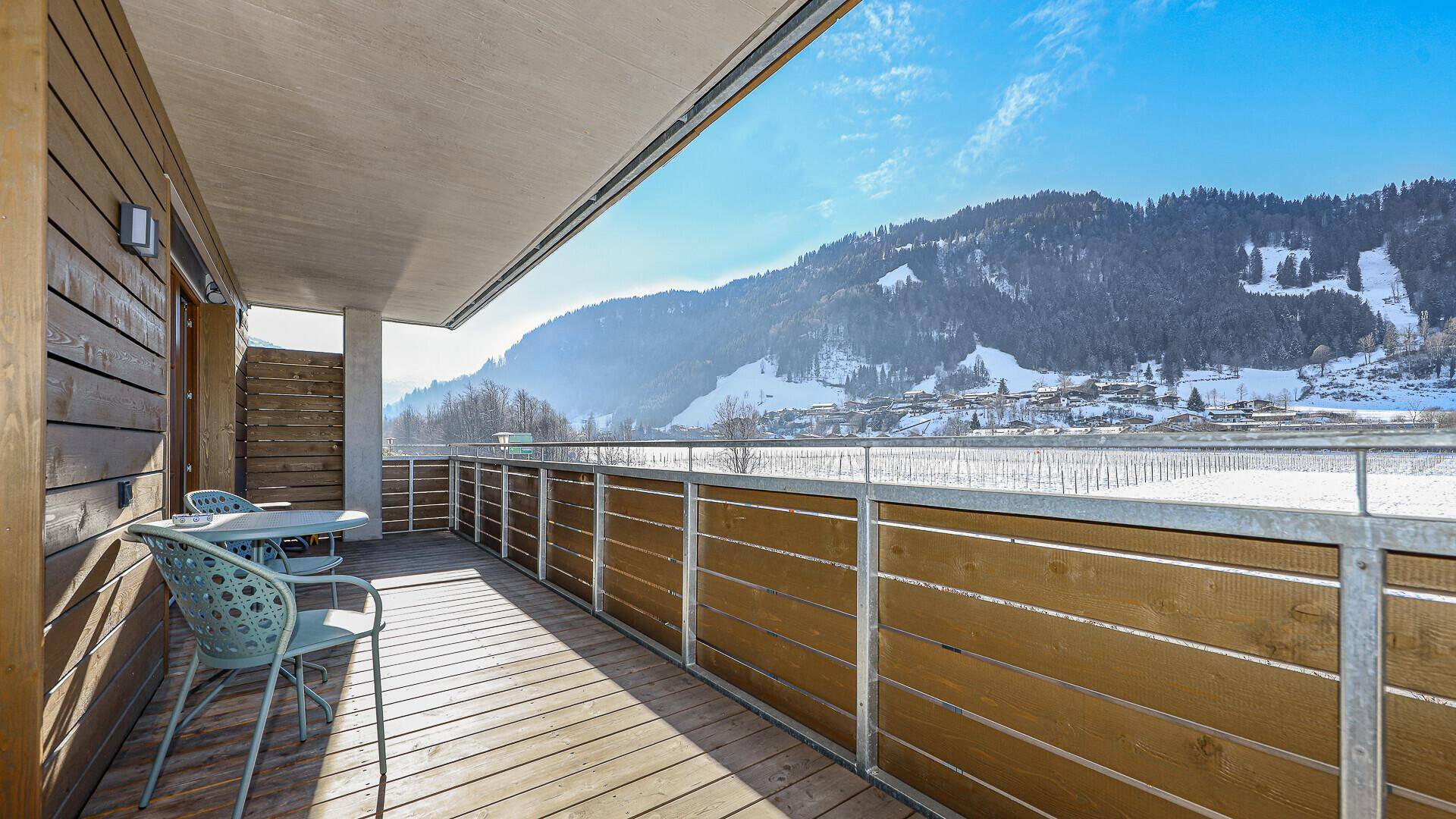Sonniger Balkon mit Holzboden und atemberaubendem Panoramablick auf die umliegenden Berge und Täler.