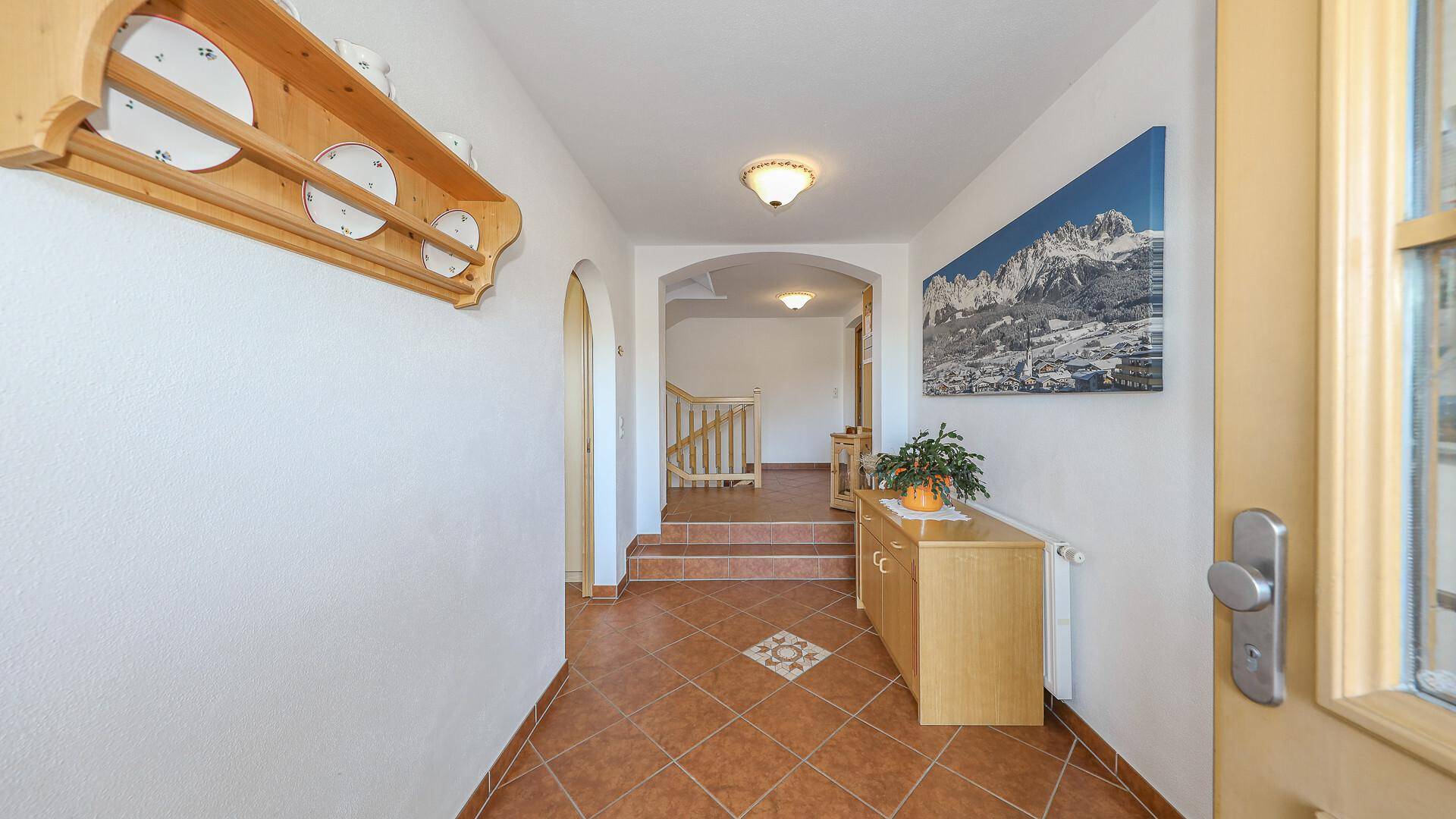 Heller Eingangsbereich mit Fliesenboden, Garderobe und Zugang zu weiteren Räumen.