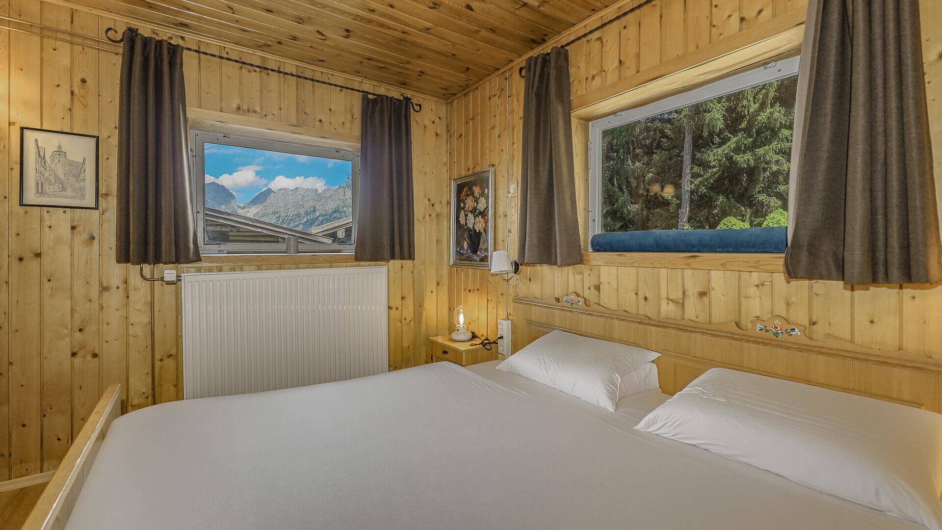 Helles Schlafzimmer mit bequemen Betten und einem malerischen Blick auf die umliegenden Berge.