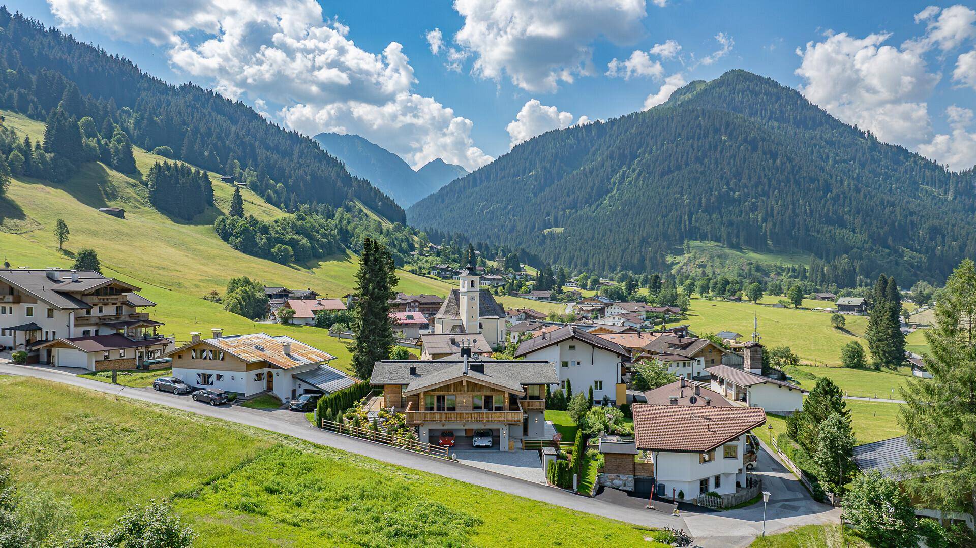 Malerisches Bergdorf mit traditionellen Häusern und üppiger grüner Landschaft unter blauem Himmel.