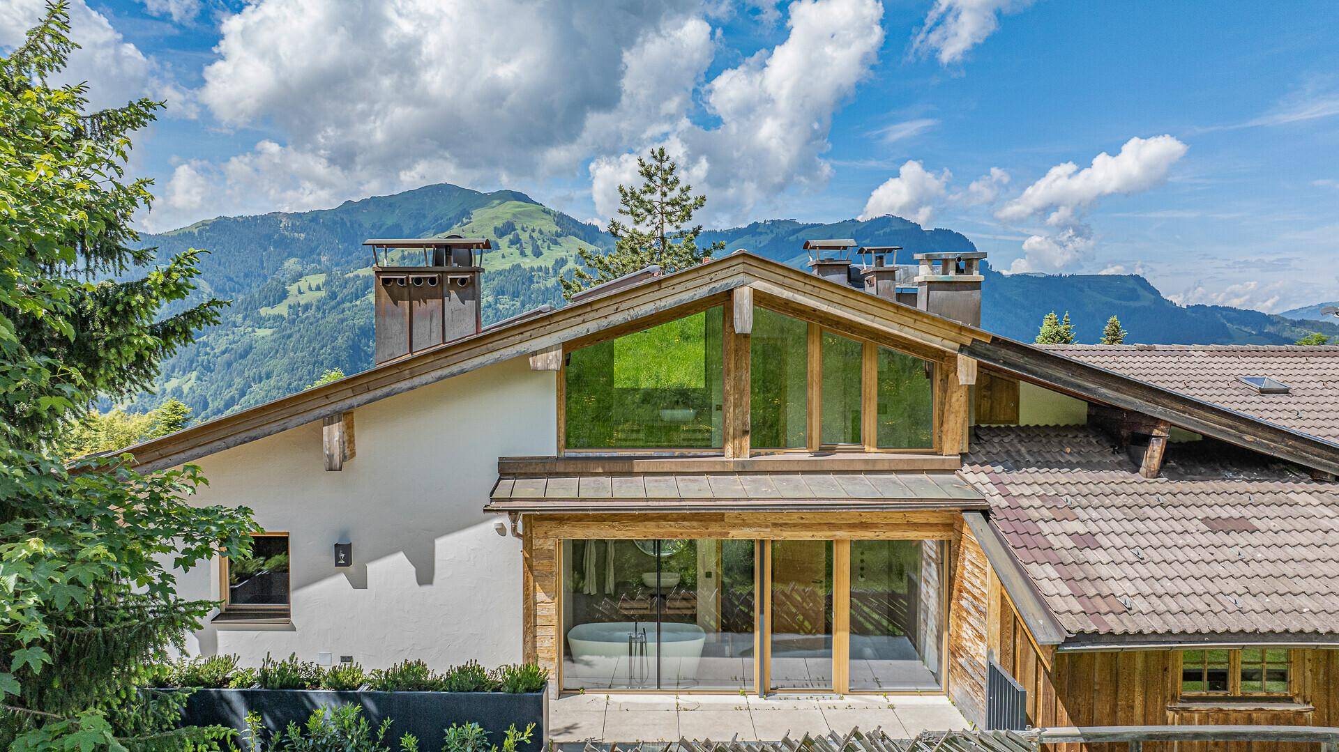 Detailansicht der modernen Holzfassade mit großen Fenstern und Bergblick.