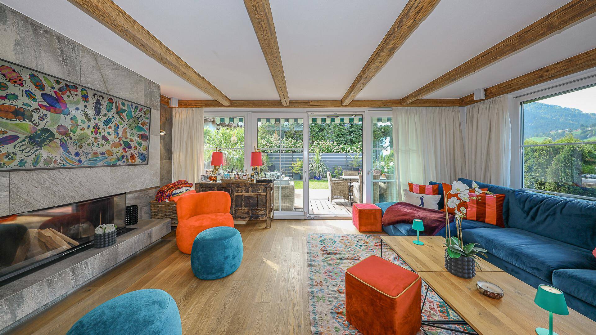 Stilvolles Wohnzimmer mit Kamin, Holzbalken und großen Schiebetüren zum Gartenbereich.
