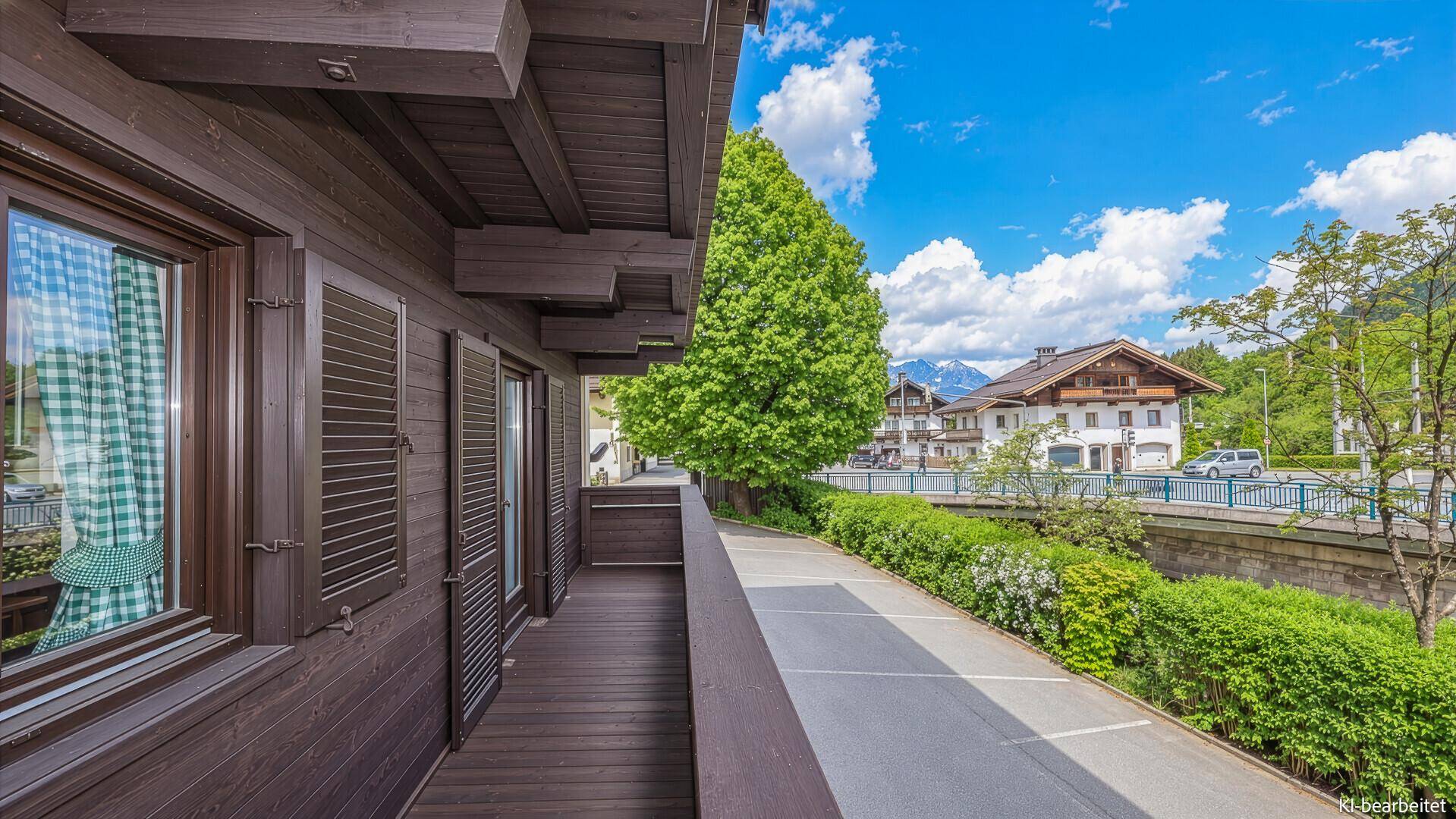 Langer Balkon mit Holzgeländer und Blick auf die Straße und die umliegende Berglandschaft.