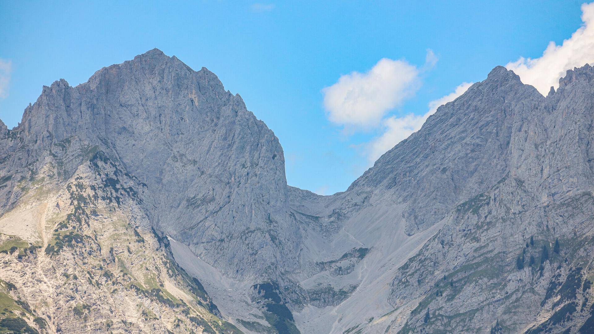Detailansicht einer schroffen Bergformation mit steilen Felswänden unter blauem Himmel.